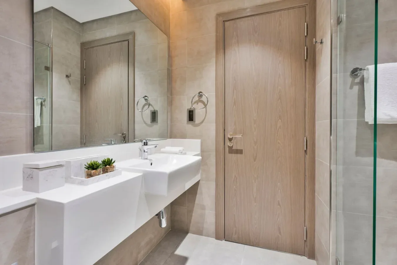Un lavabo de baño con espejo está junto a una puerta de madera.