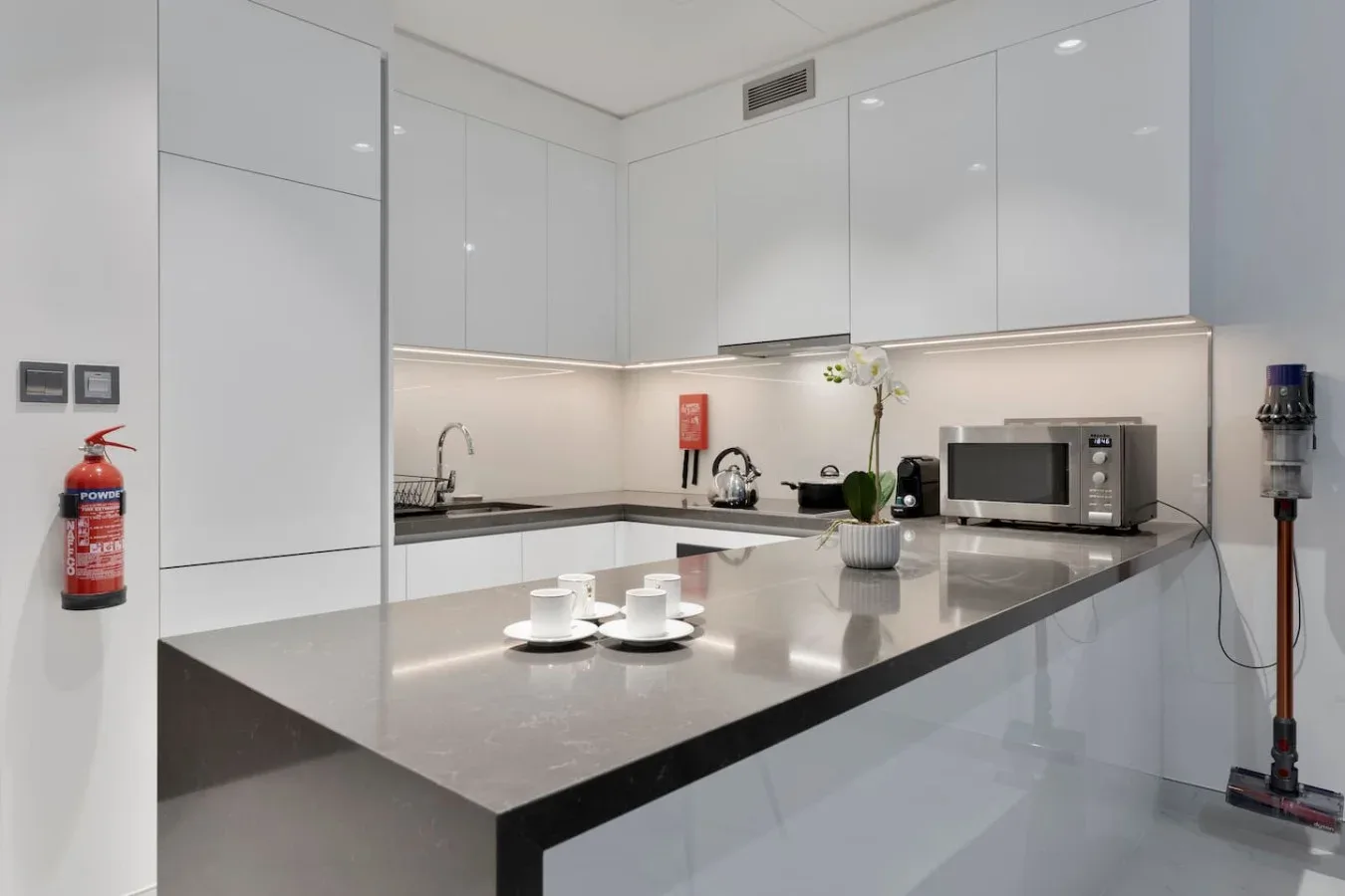 Una cocina moderna con armarios brillantes, una encimera y un microondas.