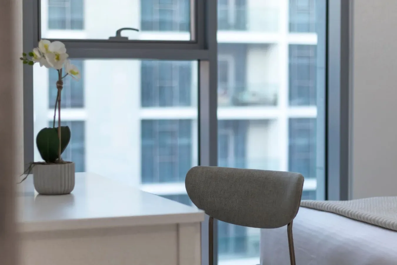 Una habitación luminosa con escritorio, asiento y ventanas grandes.