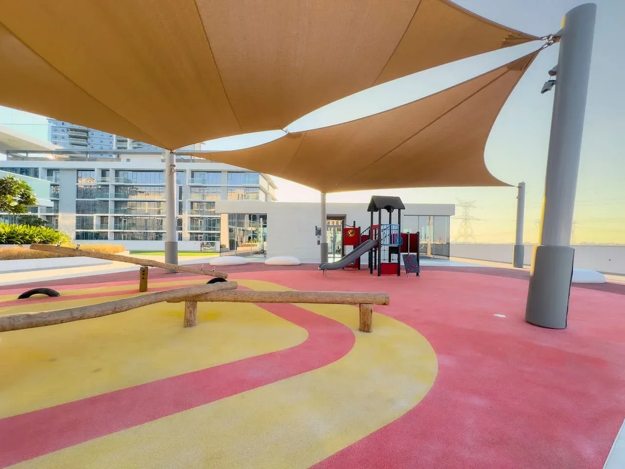 Un parque infantil al aire libre tiene suelo de colores y una pequeña estructura de juego.