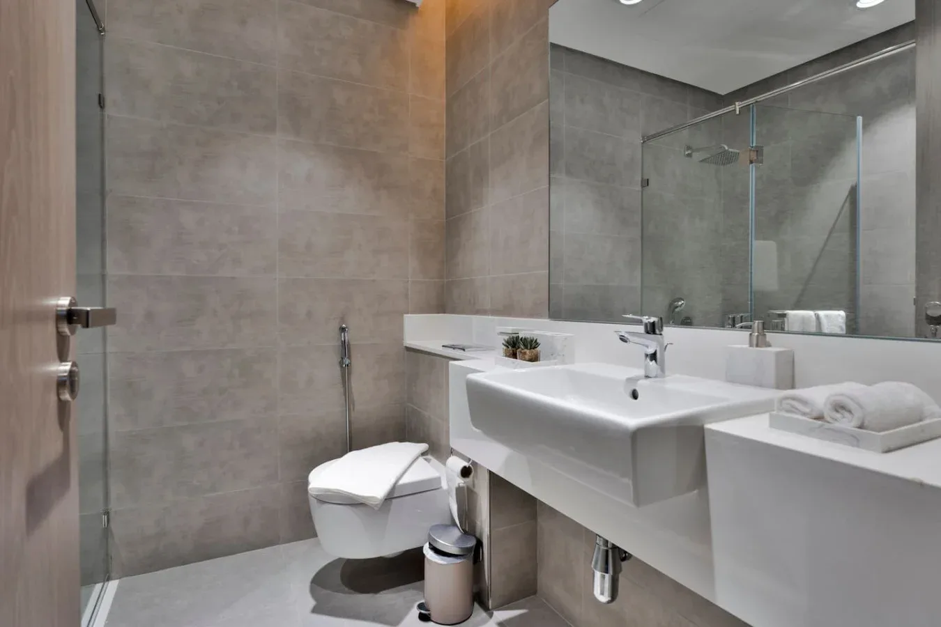 Un baño moderno con inodoro, lavabos blancos y una ducha de vidrio.