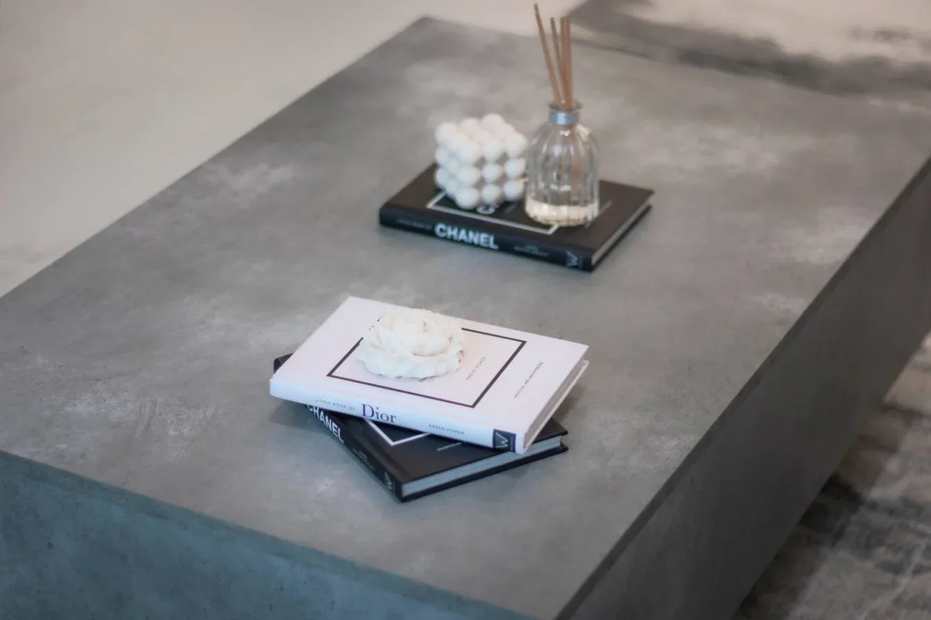 Una mesa de centro gris muestra libros apilados y un pequeño arreglo decorativo.