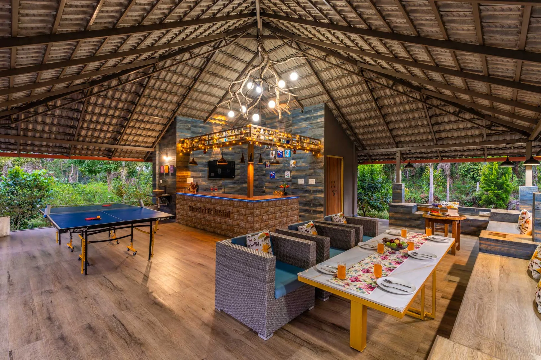 Un salón y comedor al aire libre cuenta con una barra, asientos y una mesa de ping-pong.