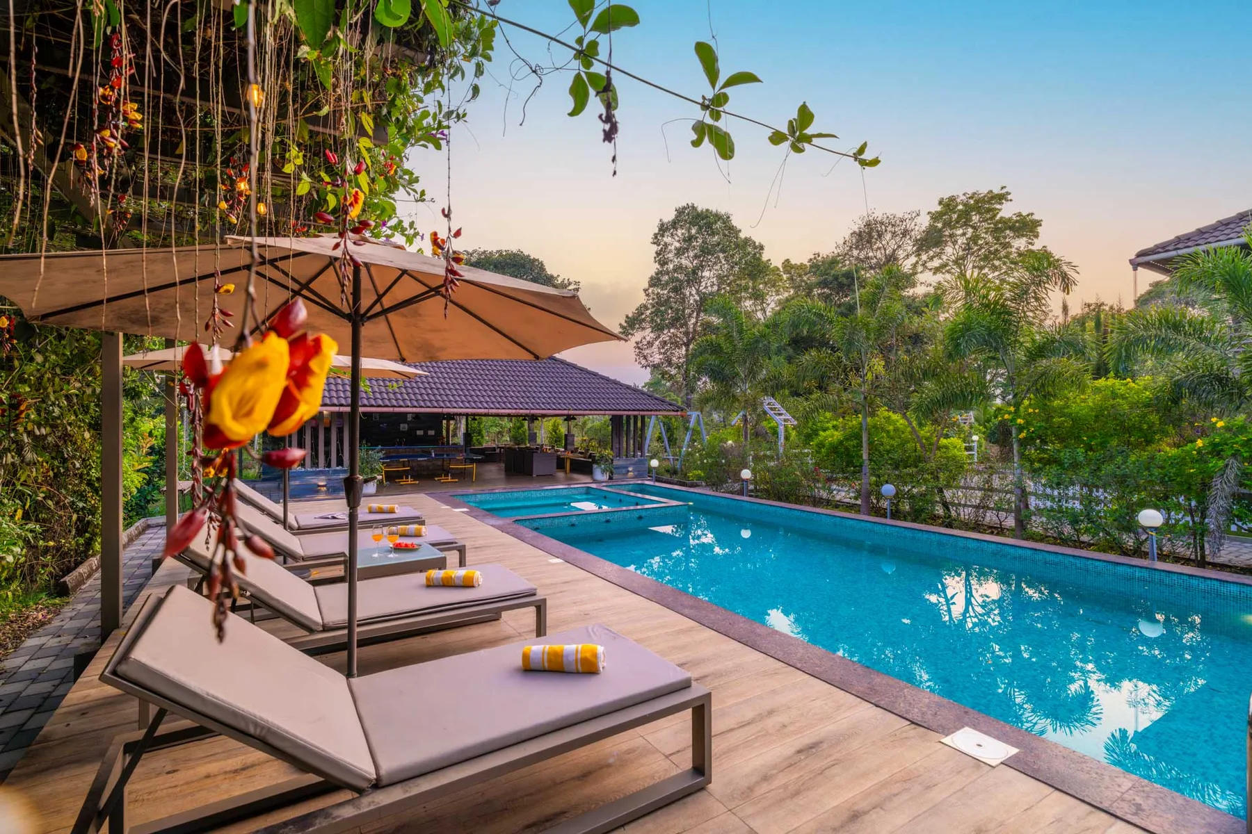 Una piscina al aire libre junto a una terraza de madera con asientos.
