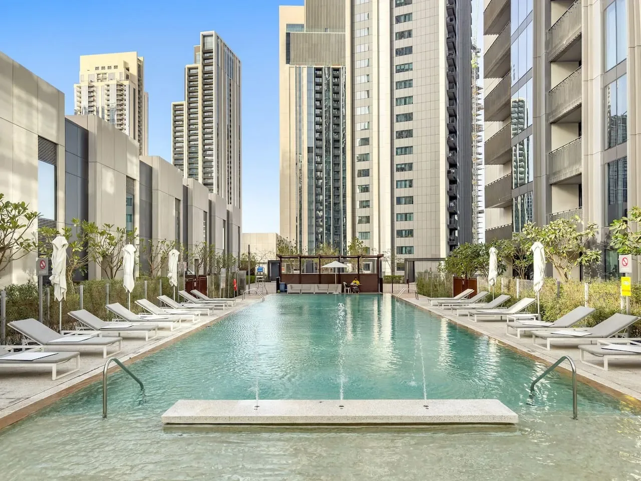 Una piscina al aire libre está rodeada de tumbonas y edificios altos de la ciudad.