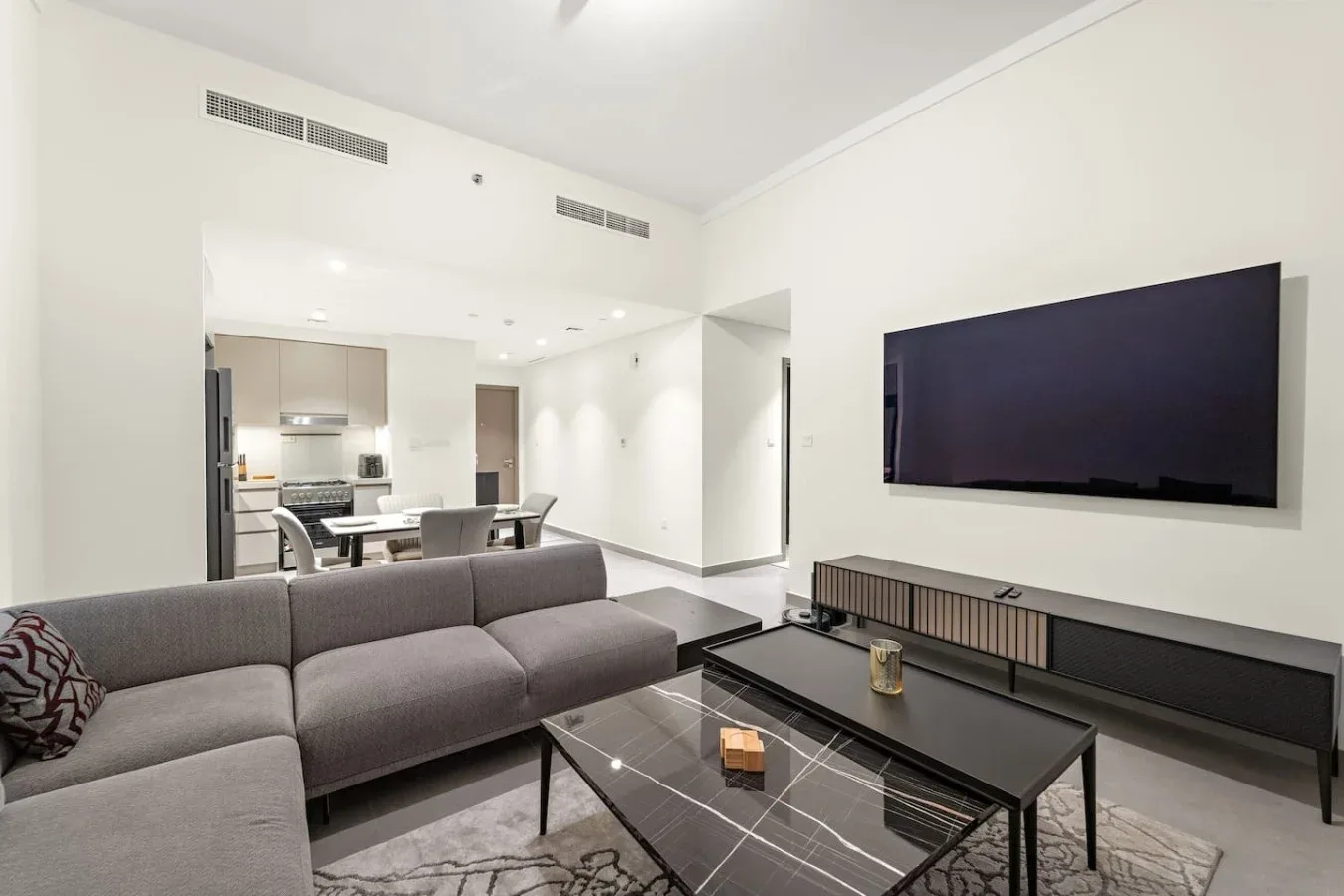 A living room with a sectional sofa, coffee table, and wall-mounted television.