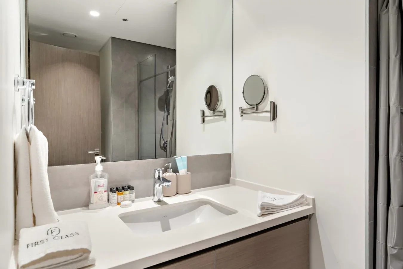 A bathroom vanity with a wide mirror, sink, and neatly arranged toiletries.