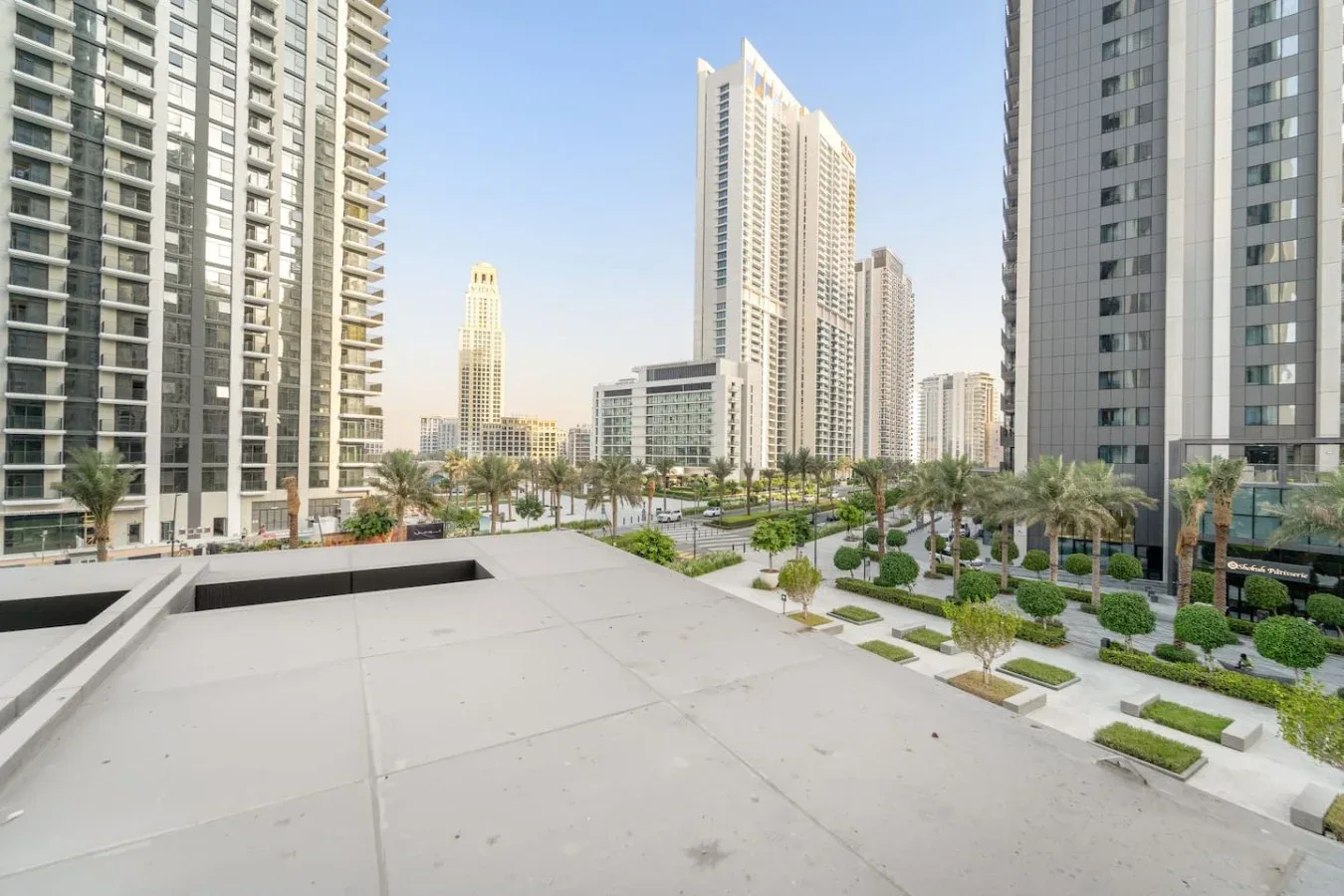 A paved terrace overlooks landscaped grounds and tall city buildings.