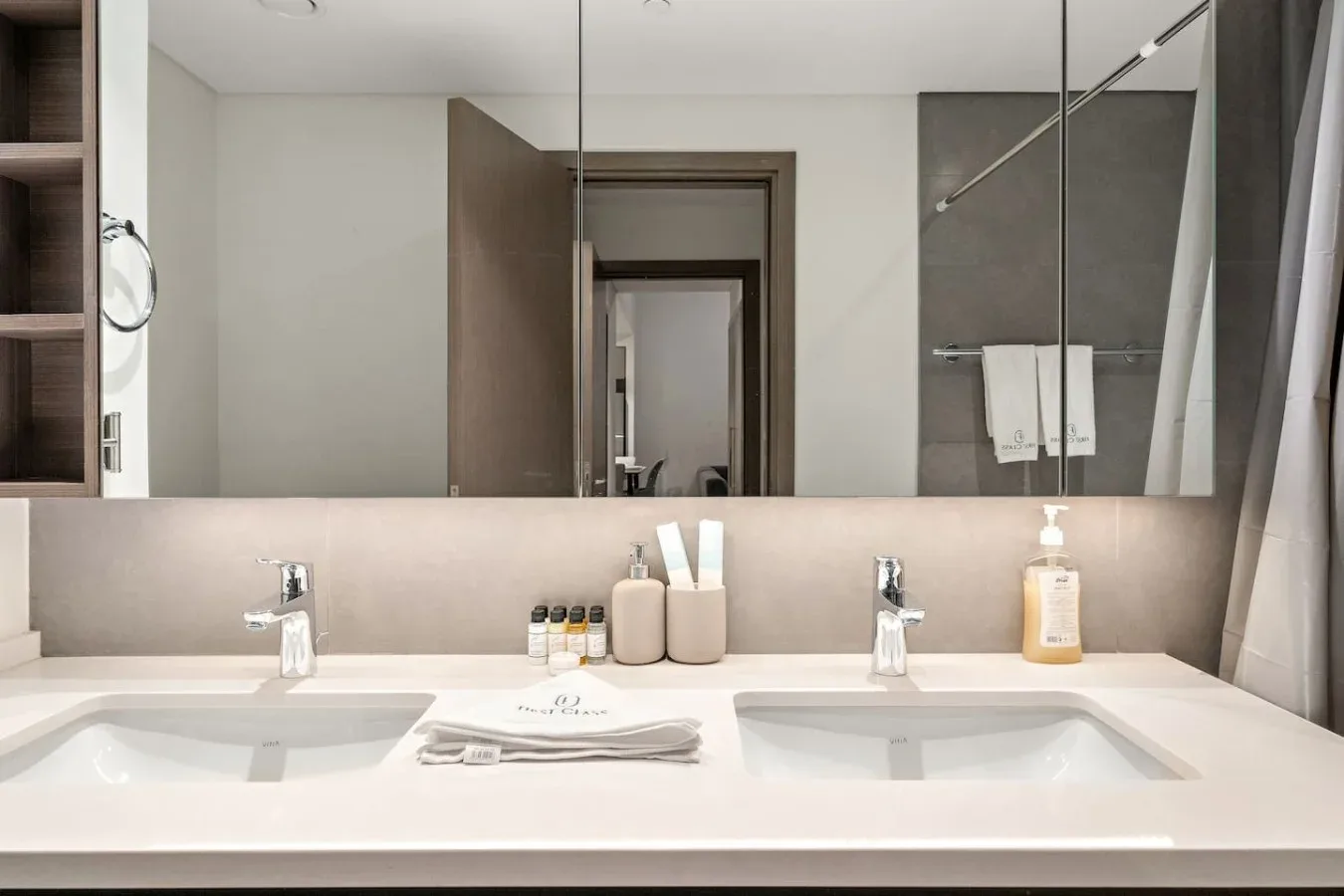 A bathroom vanity with two sinks sits beneath a wide mirror.