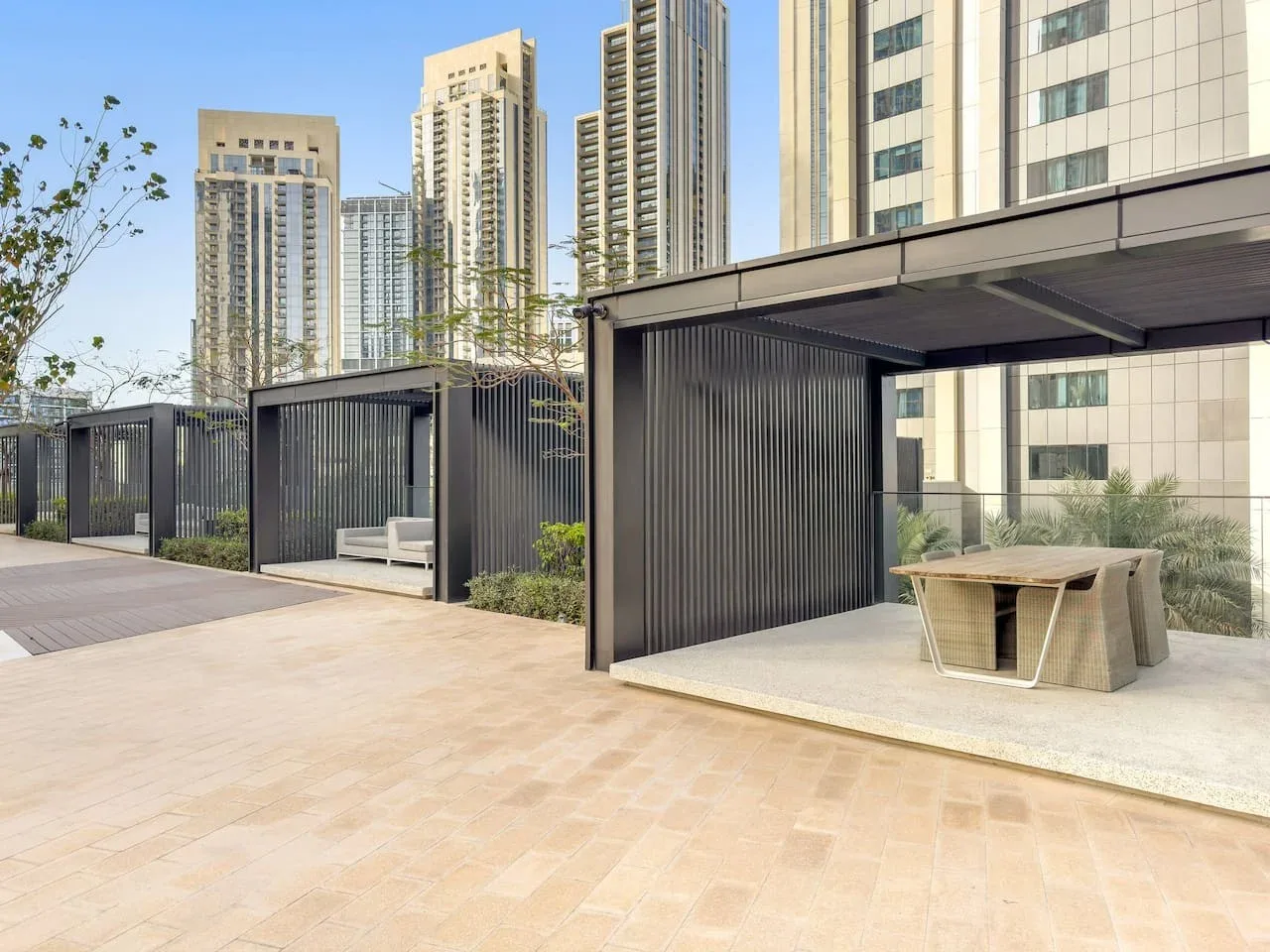 A rooftop terrace with shaded seating areas and tall buildings in the background.