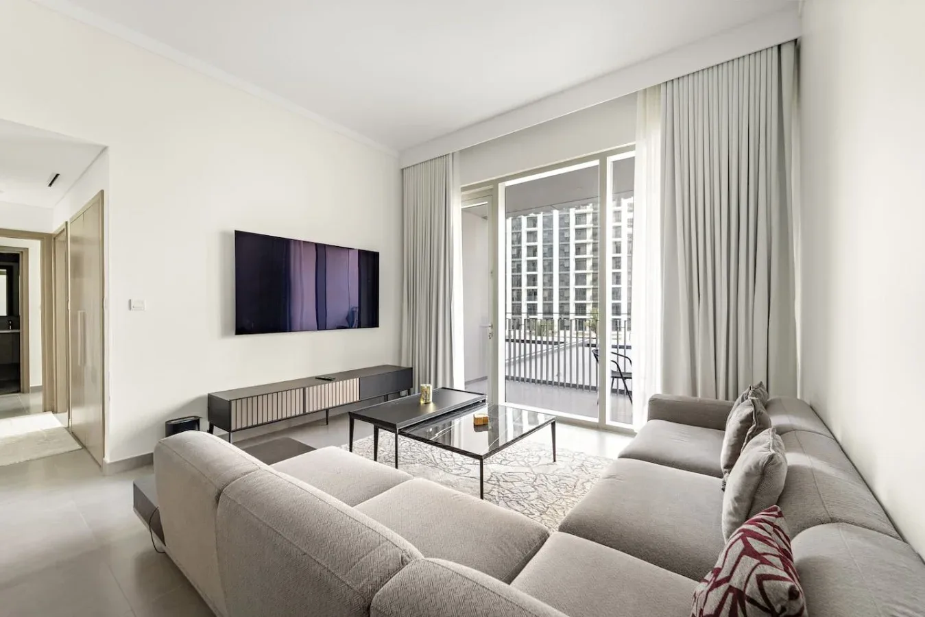 A bright living room with seating and glass doors opening onto a balcony.