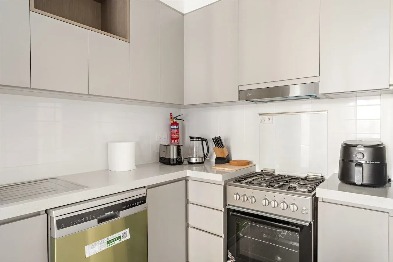 A bright kitchen with white cabinets and cooking appliances along the counters.