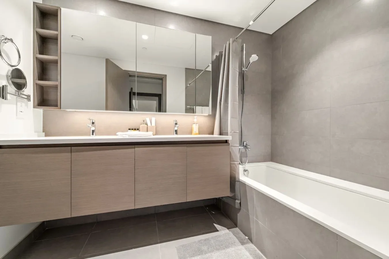 A modern bathroom with a long vanity, mirrored cabinets, and a bathtub.