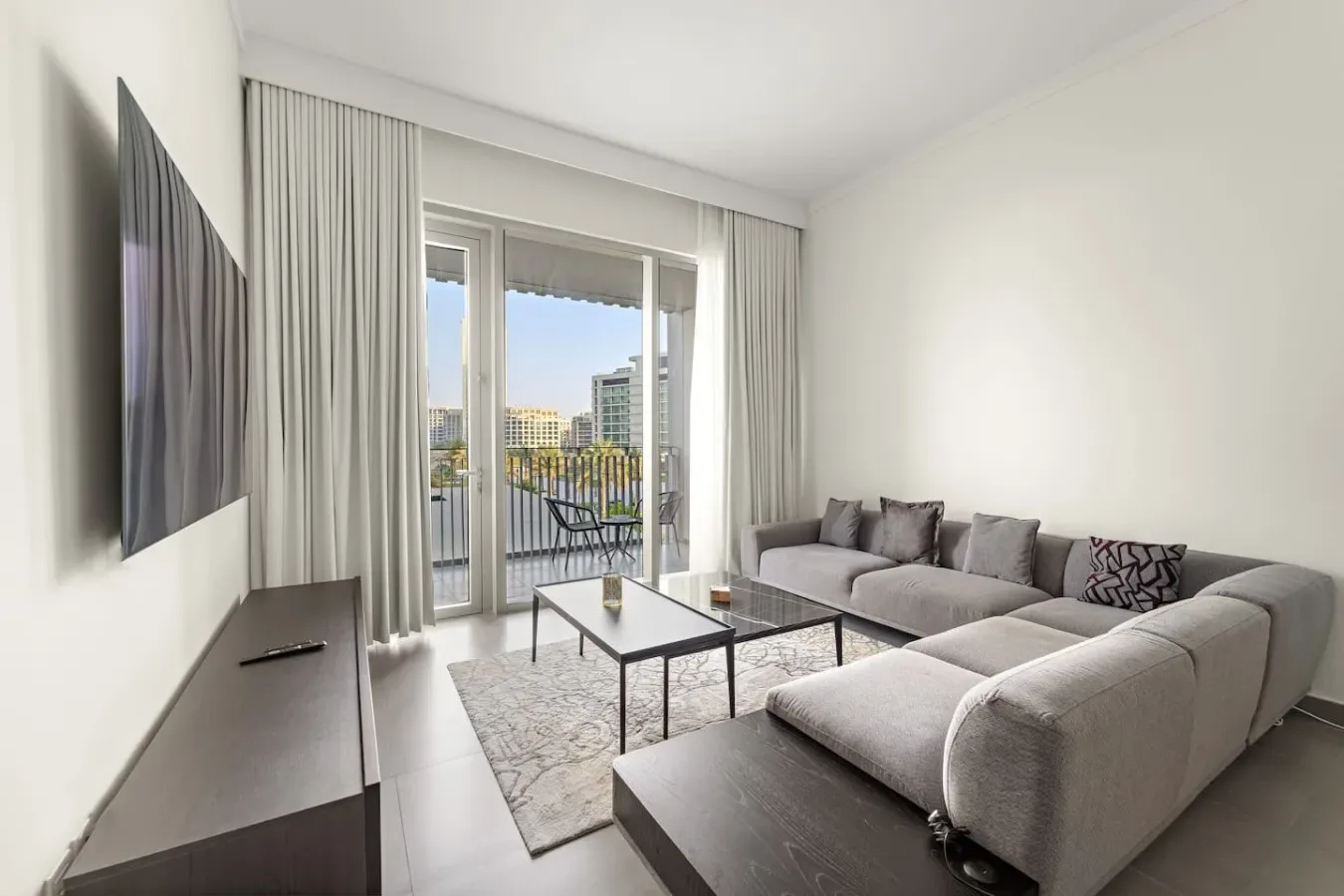 A bright living room with a sectional seating area beside glass balcony doors.