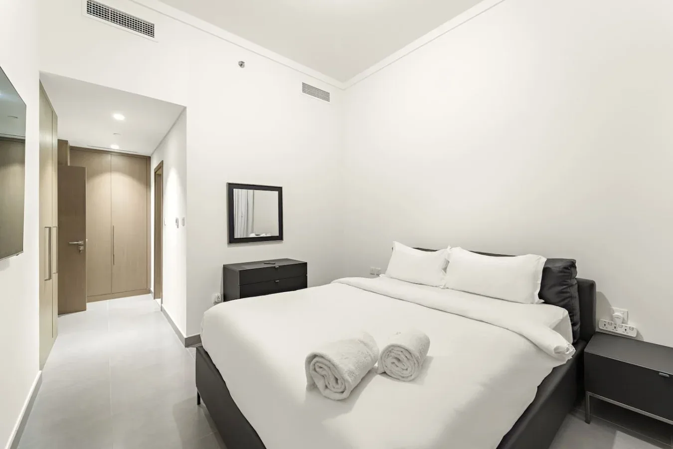 A bright bedroom with a large bed and folded towels.