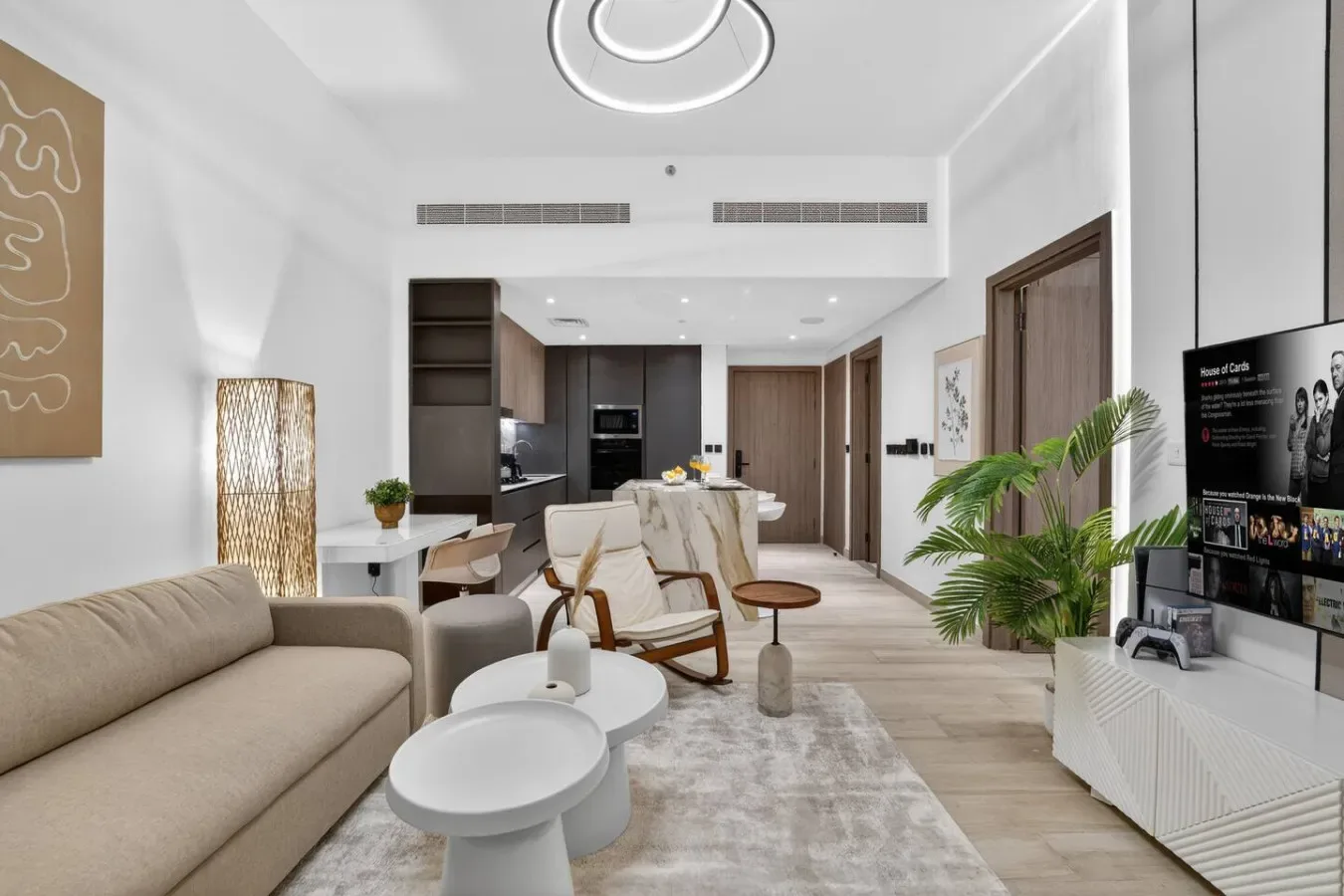 Una sala luminosa con asientos, una mesa de centro y una cocina abierta al fondo.