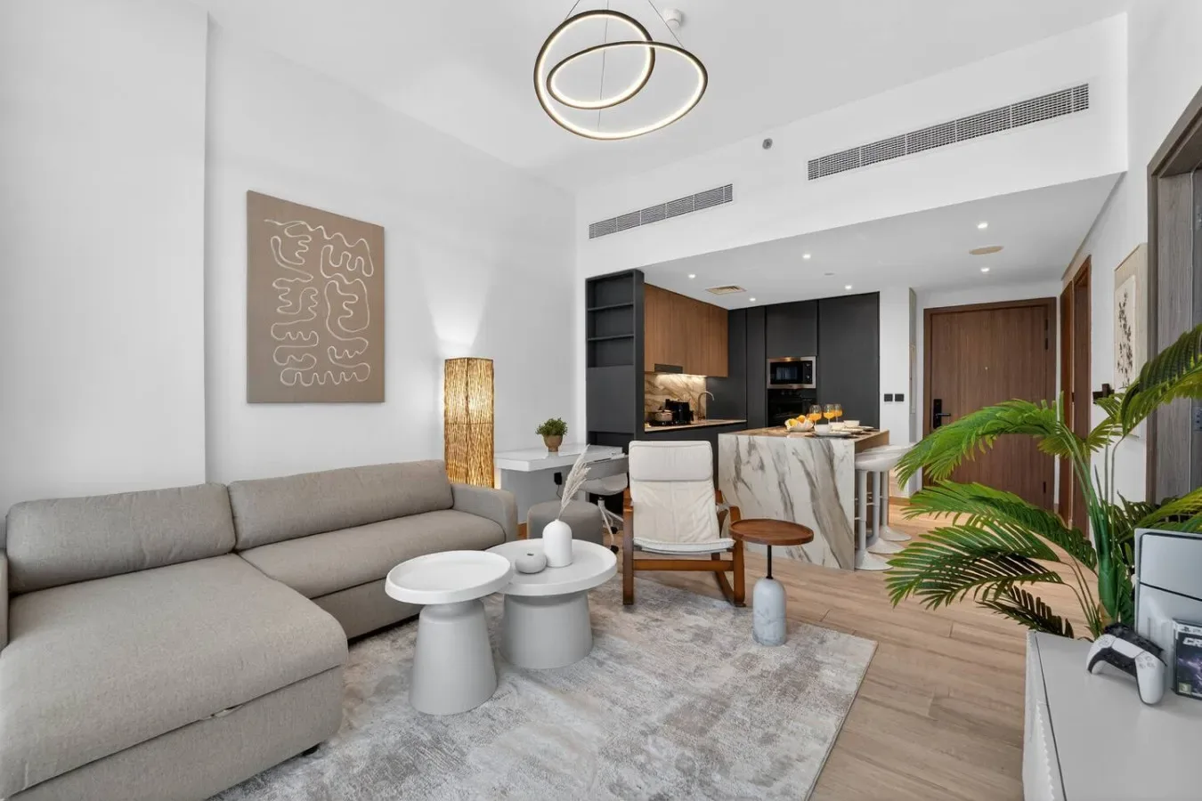 Una luminosa sala de estar se abre a la cocina, con un sofá gris y una mesa de comedor.