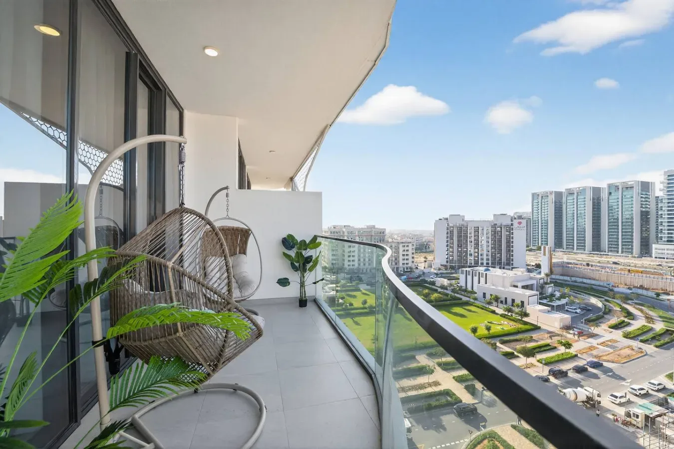 Un balcón con una silla colgante y vistas a los edificios de alrededor.