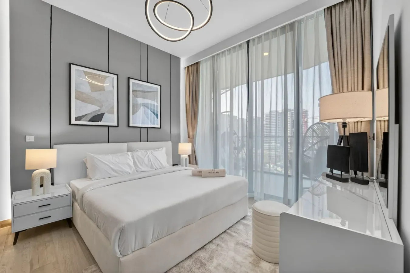 Un dormitorio con una cama grande, mesitas de noche y ventanales.