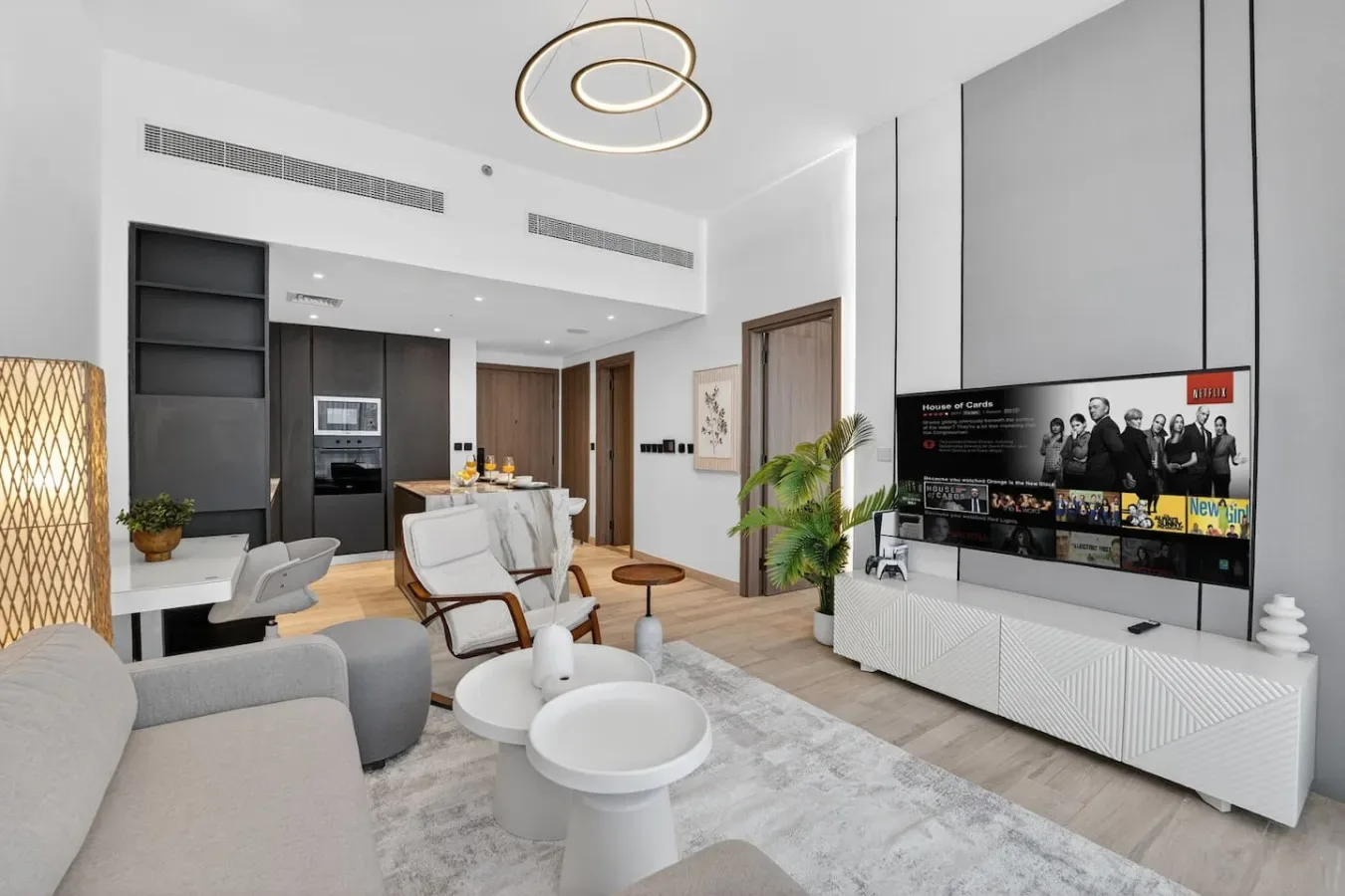 Una luminosa sala de estar moderna con asientos, un televisor y una cocina abierta.