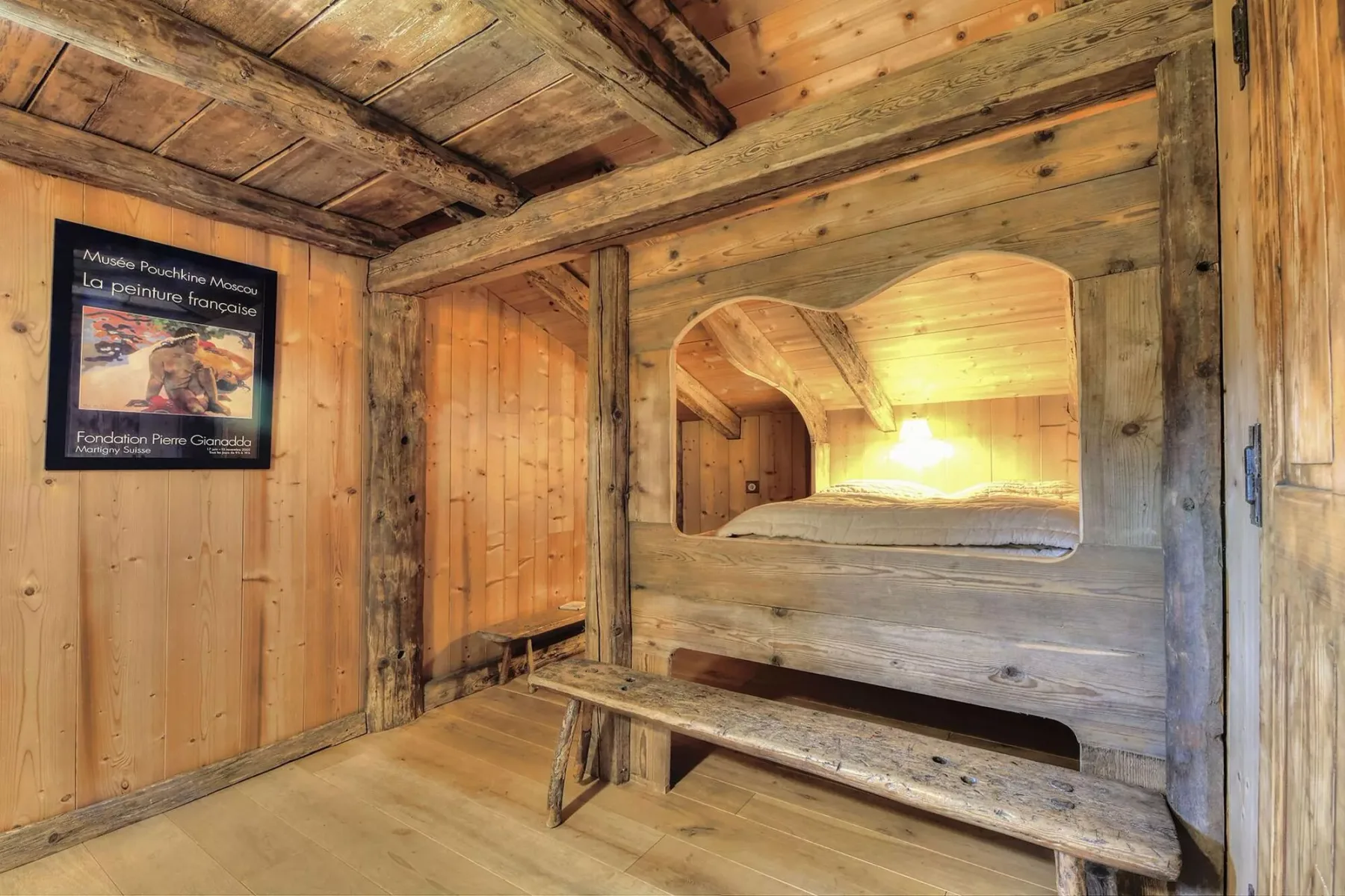 A wood-paneled interior with a long bench beneath an arched opening.
