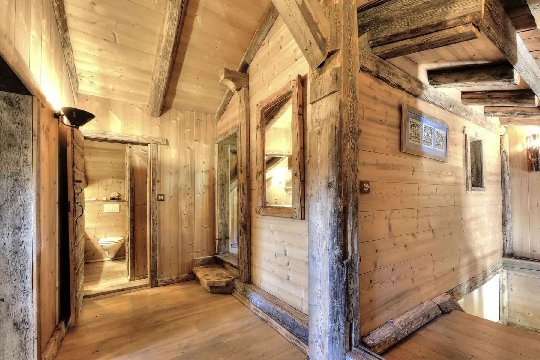 A rustic wooden interior hallway with an open doorway to a bathroom.
