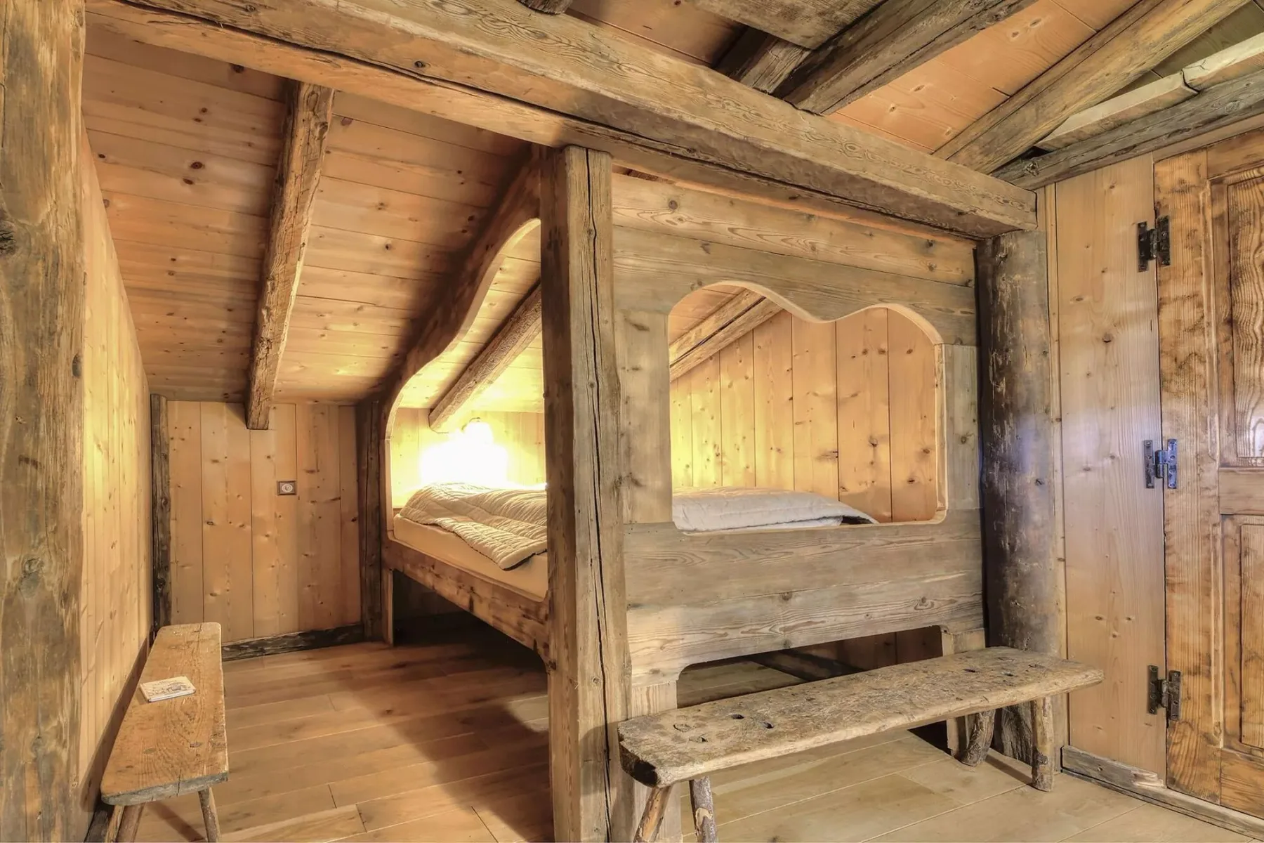 A rustic wooden bedroom with a built-in bed and exposed beams.