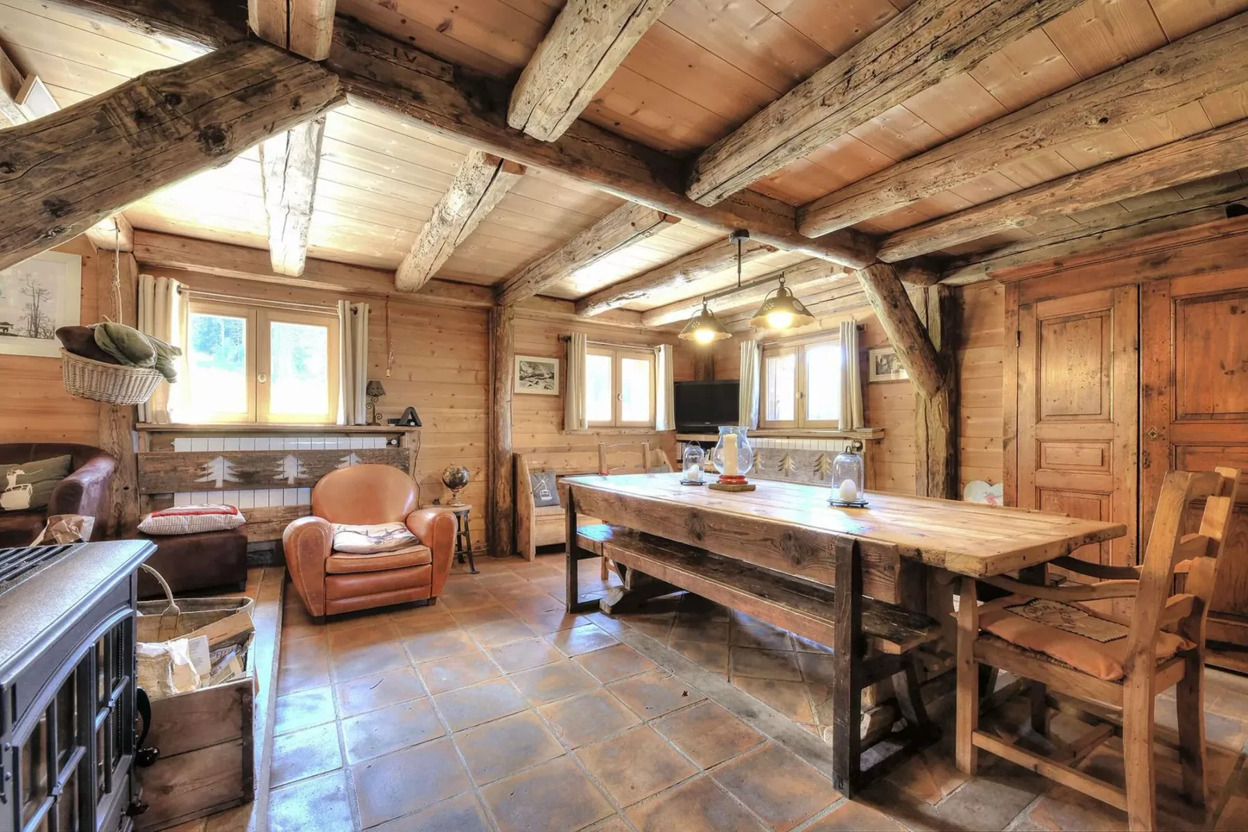 A rustic dining room with a large wooden table and adjoining seating area.