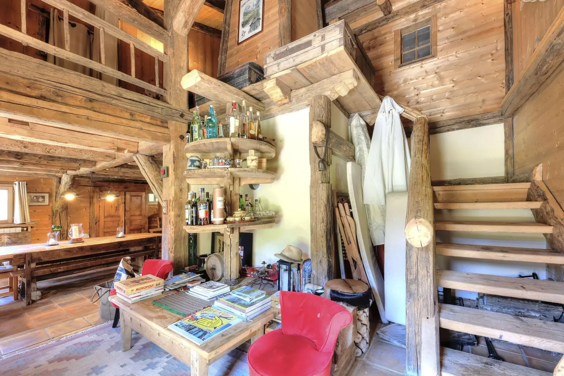 A rustic wooden interior with a table, red seating, and a staircase.