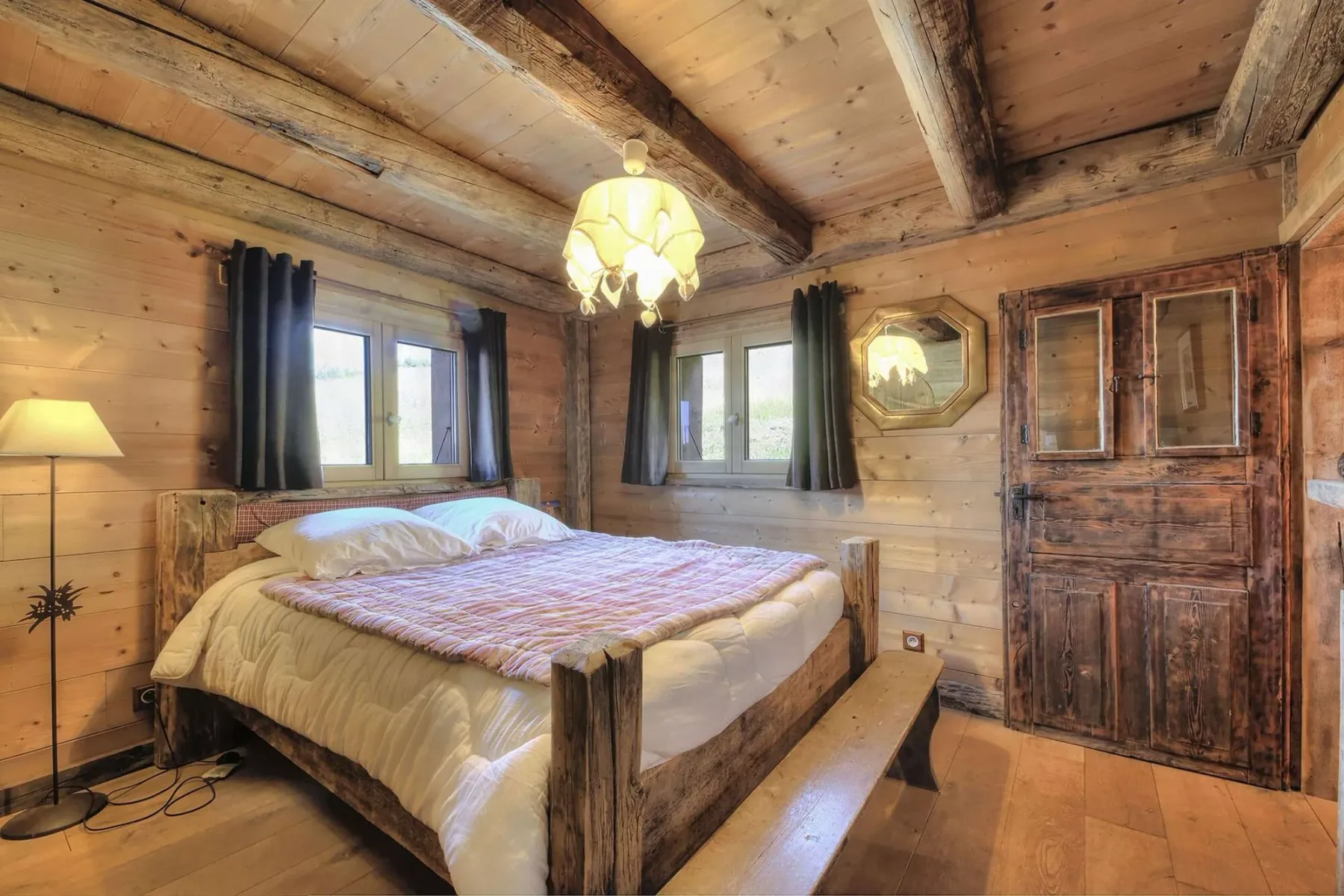 A bedroom with a bed, wood-paneled walls, and windows with dark curtains.