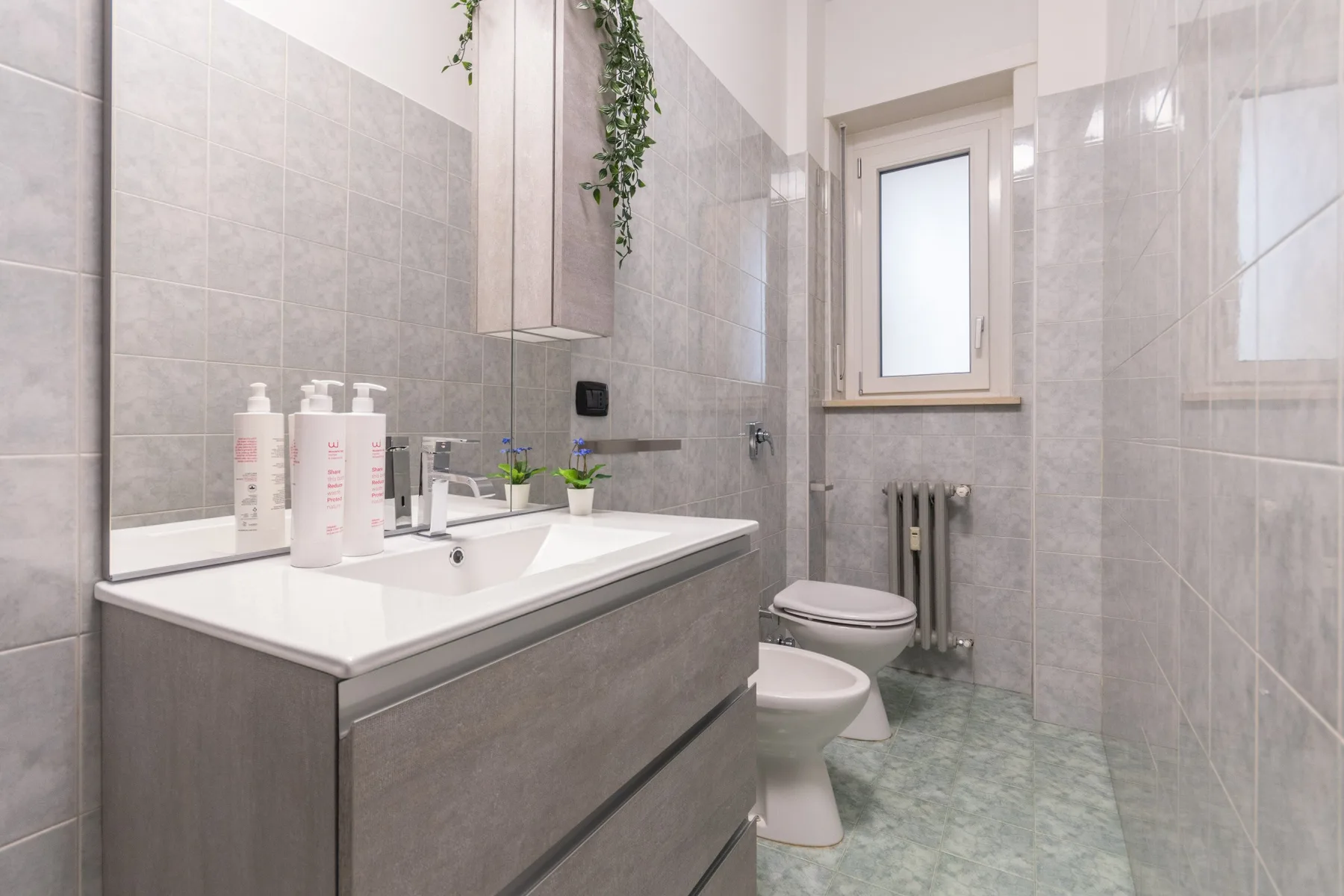 Un baño alicatado con lavabo, inodoro y ventana esmerilada.