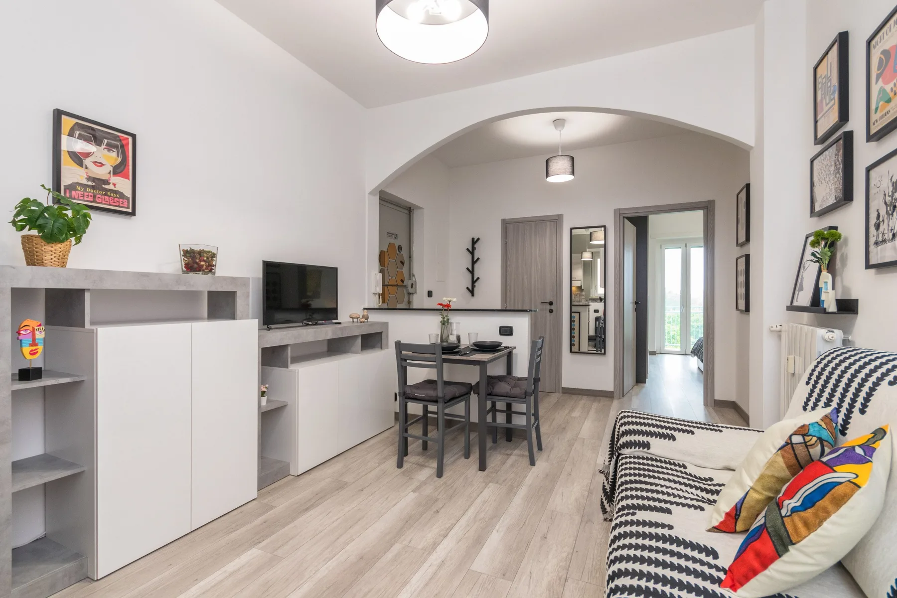 A bright living and dining area features a table beneath an arched opening.