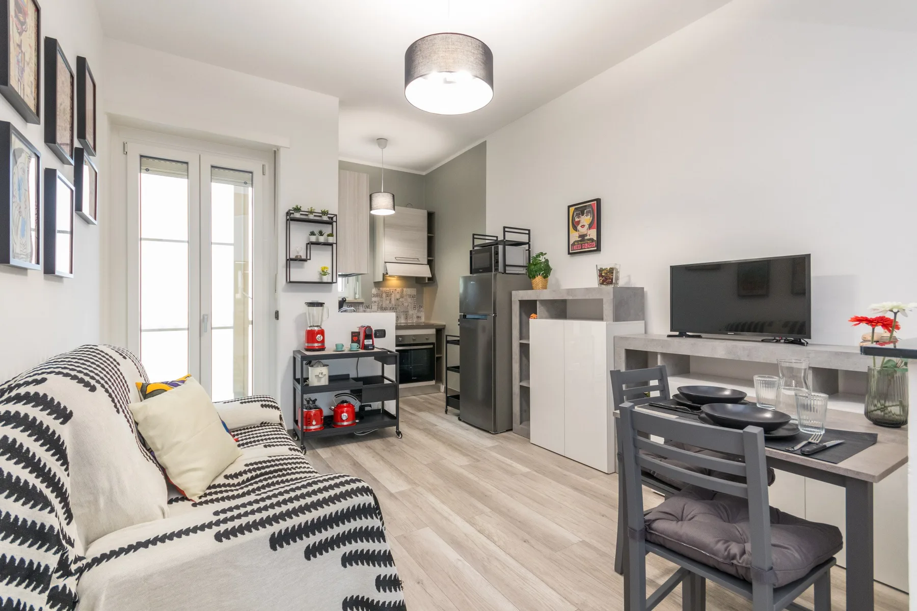 Una zona de estar compacta combina asientos estampados, una mesa de comedor y una pequeña cocina.