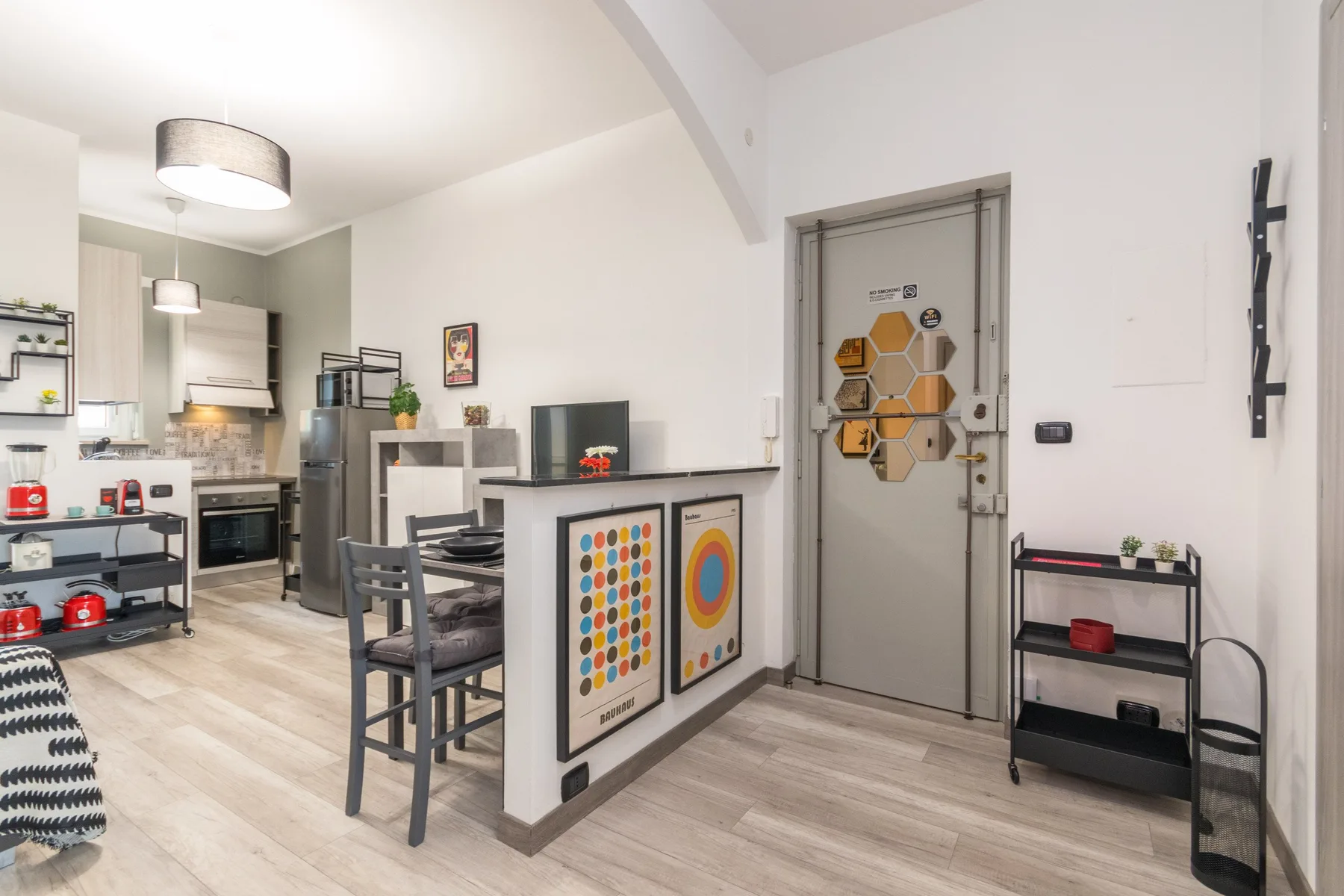 Una cocina y comedor de planta abierta con mesa, asientos y arte colorido en la pared.