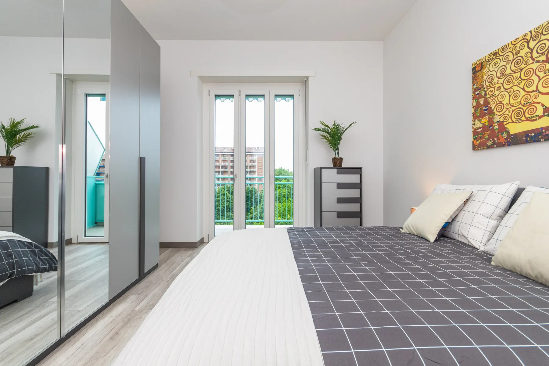 Un dormitorio con cama, armario con espejo y puertas de cristal que dan a un balcón.
