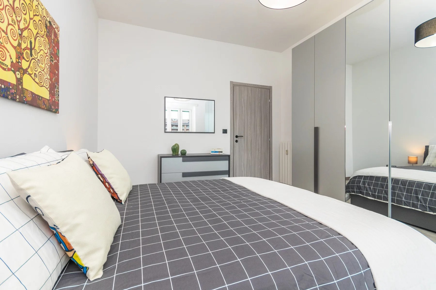 Un dormitorio con una cama tendida y puertas de armario espejadas.