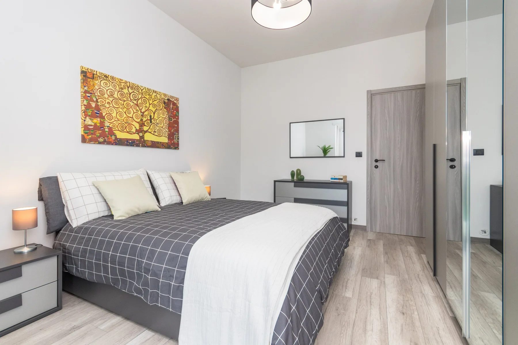 Un dormitorio con una cama grande, arte mural y puertas de armario con espejo.
