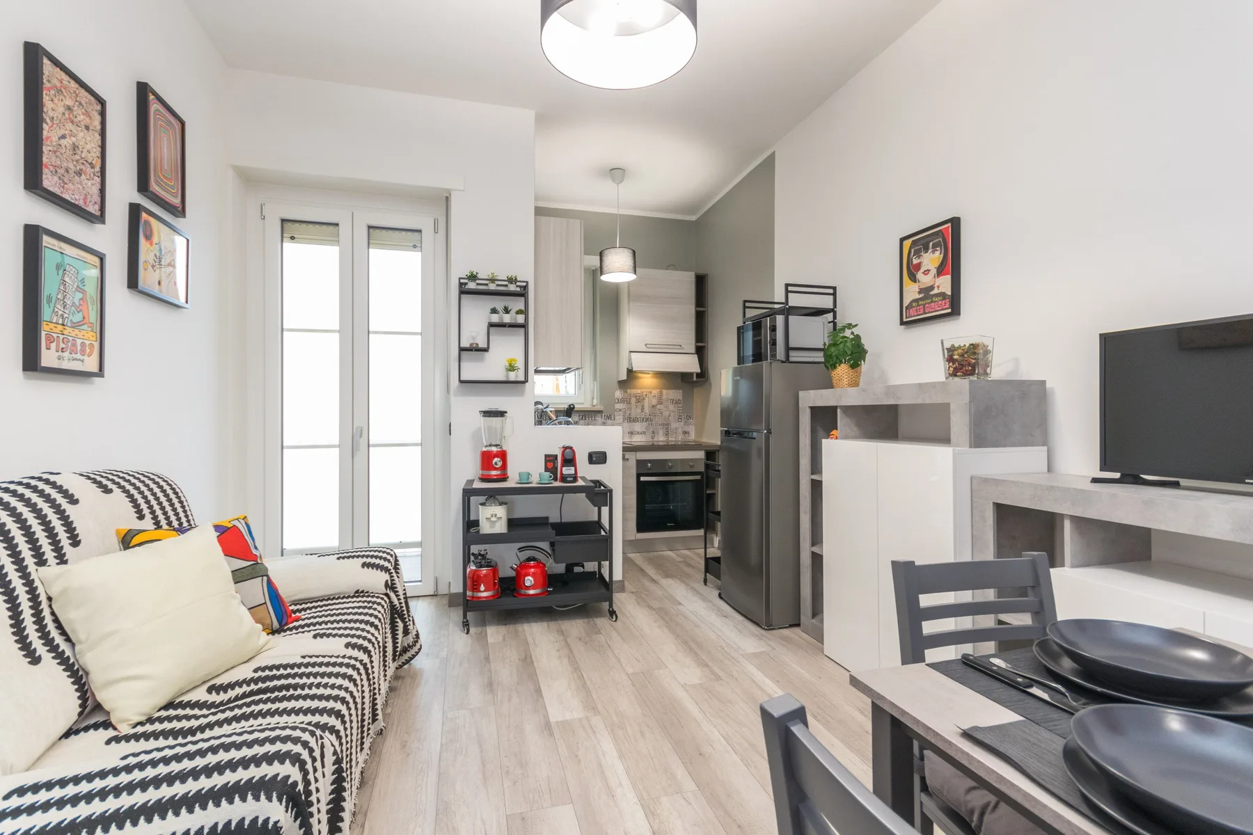 A combined living, dining, and kitchen area with patterned seating and a compact kitchen.