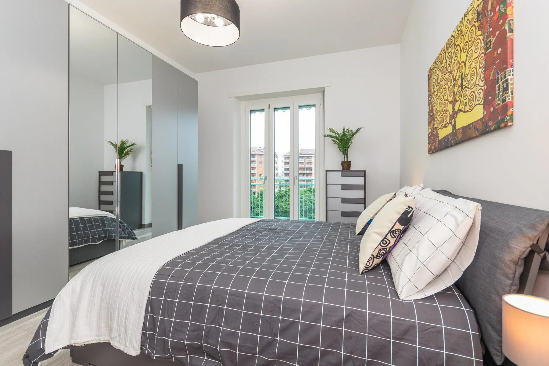 Un dormitorio con una cama bien tendida y armarios con espejo.