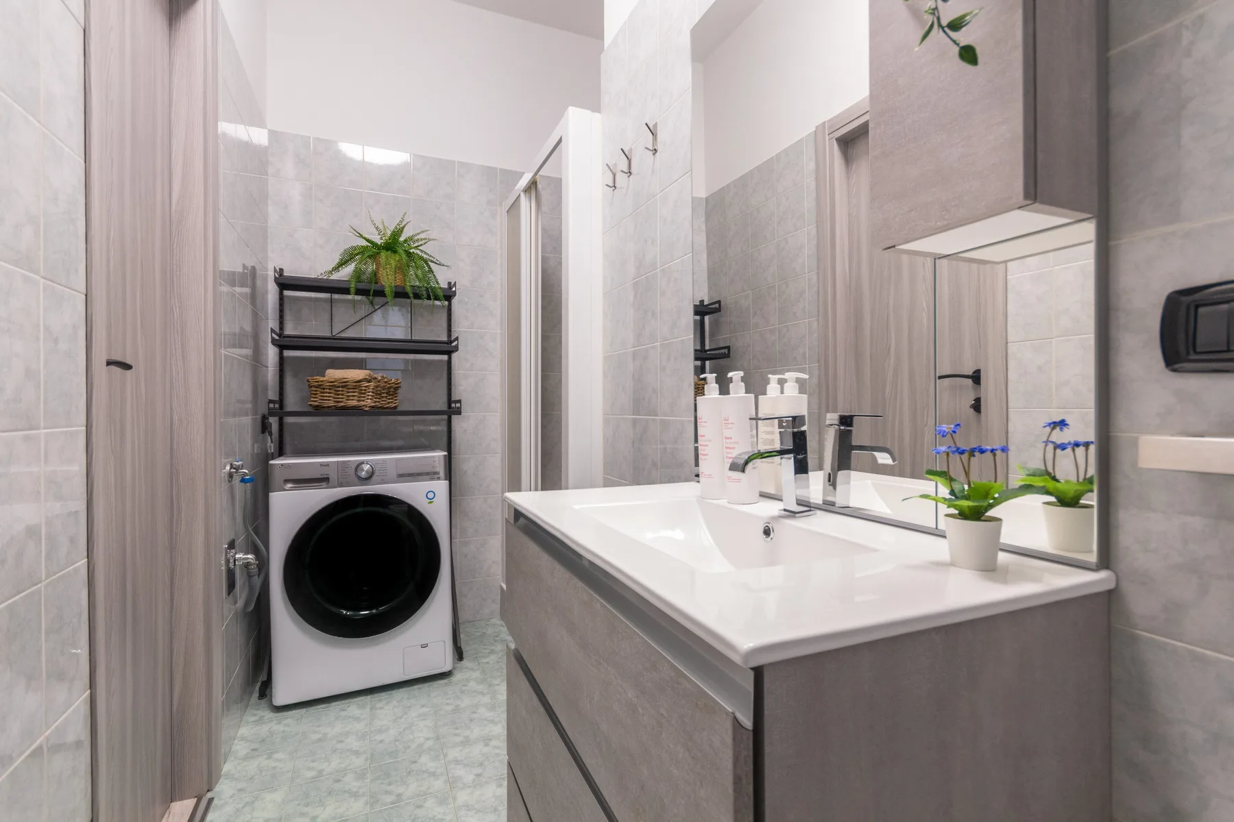 Un baño moderno con una lavadora junto al lavabo y el espejo.