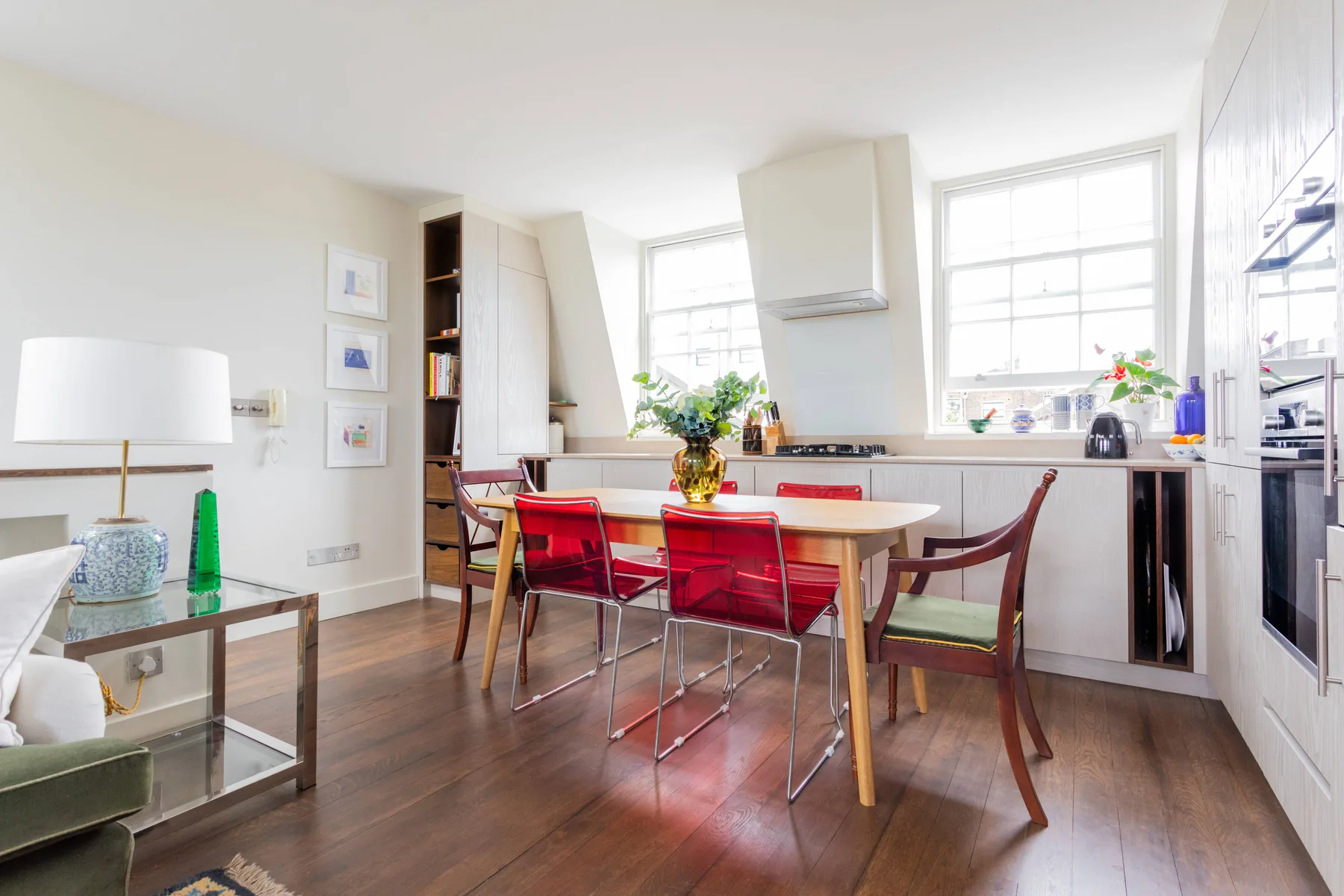 A bright kitchen and dining area with a wooden table and red seating.