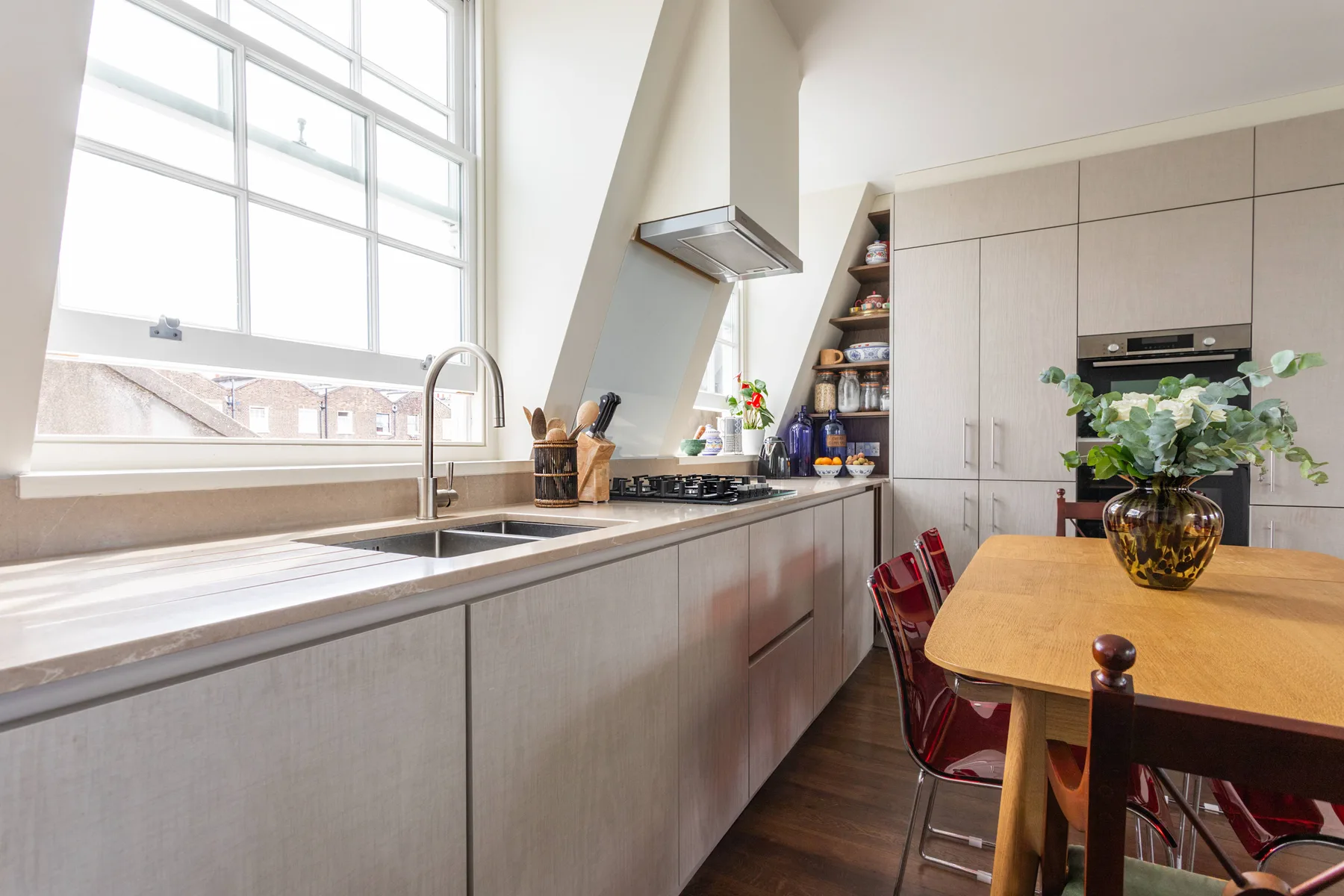 A bright kitchen with a long counter, sink, and dining table.