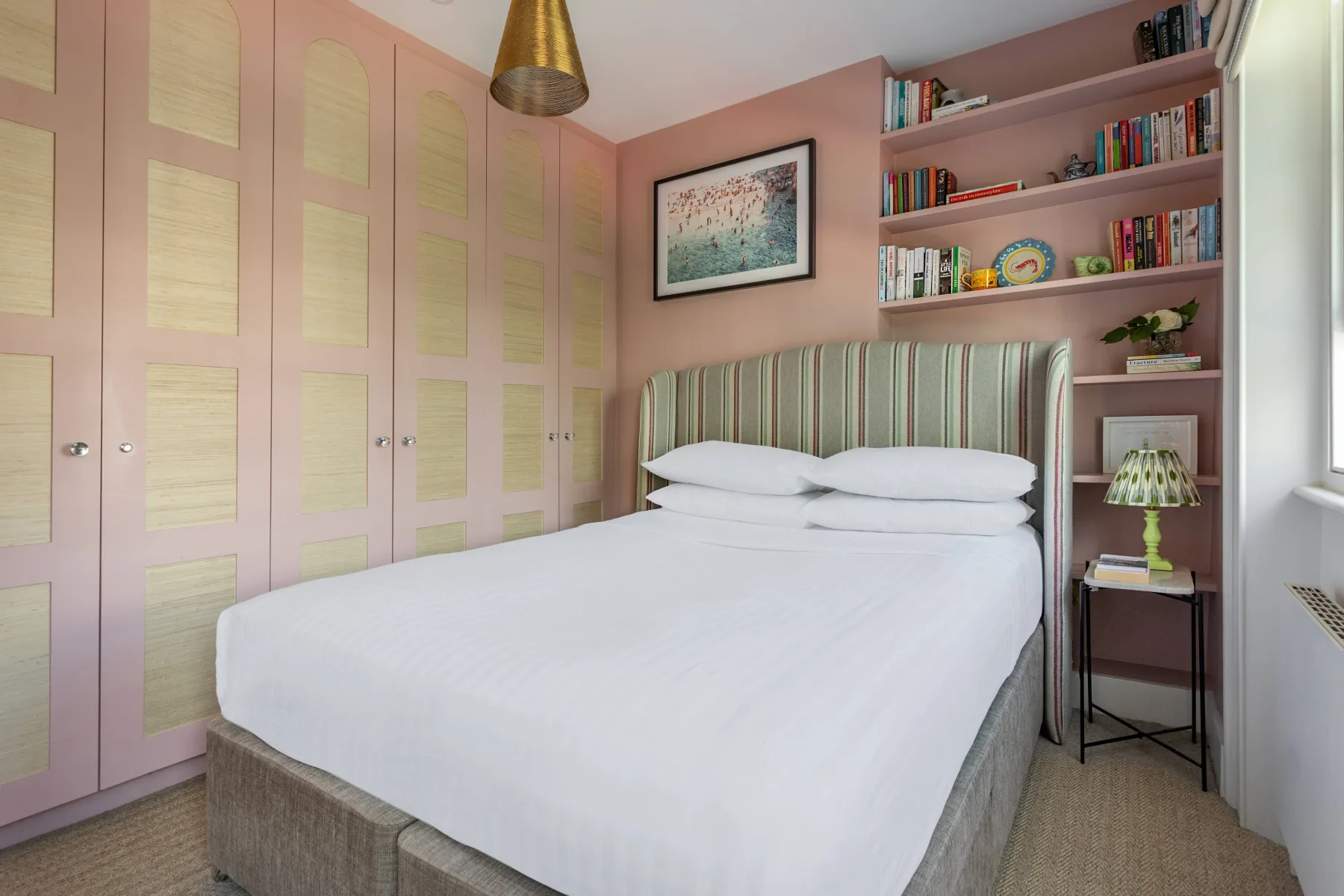 A bedroom with a neatly made bed and built-in wardrobes.