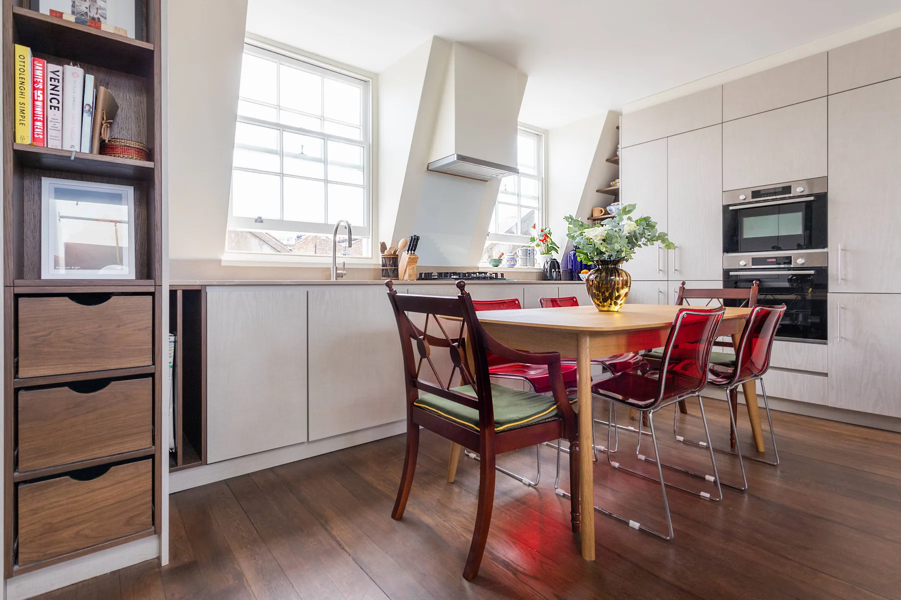 A bright kitchen and dining area with a wooden table and red seating.