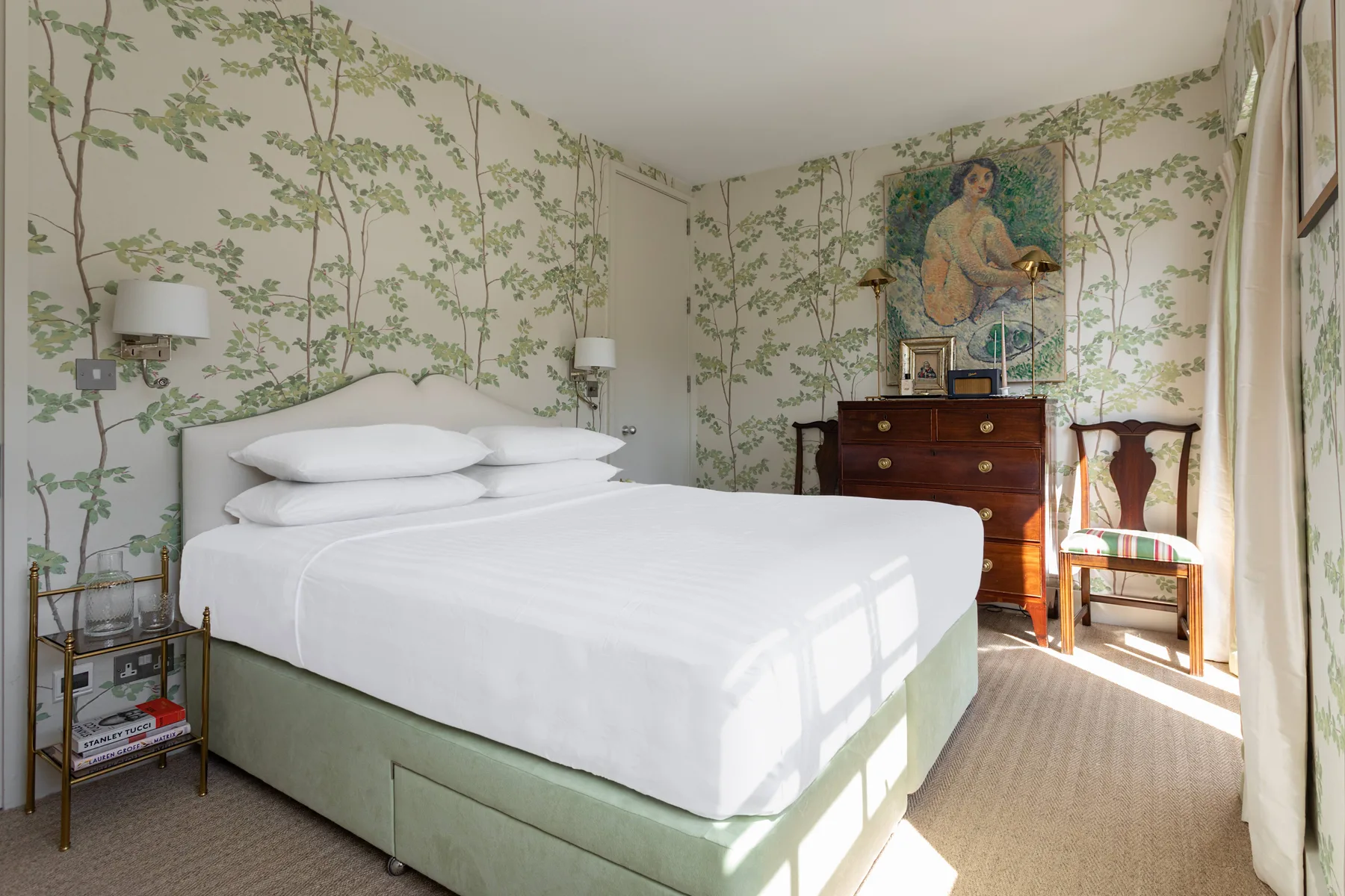 A bedroom with a neatly made bed and a wooden dresser.