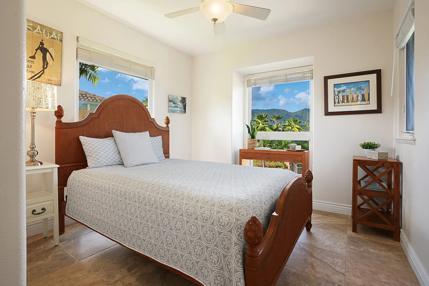 A bedroom with a wooden bed, patterned bedding, and windows overlooking greenery.