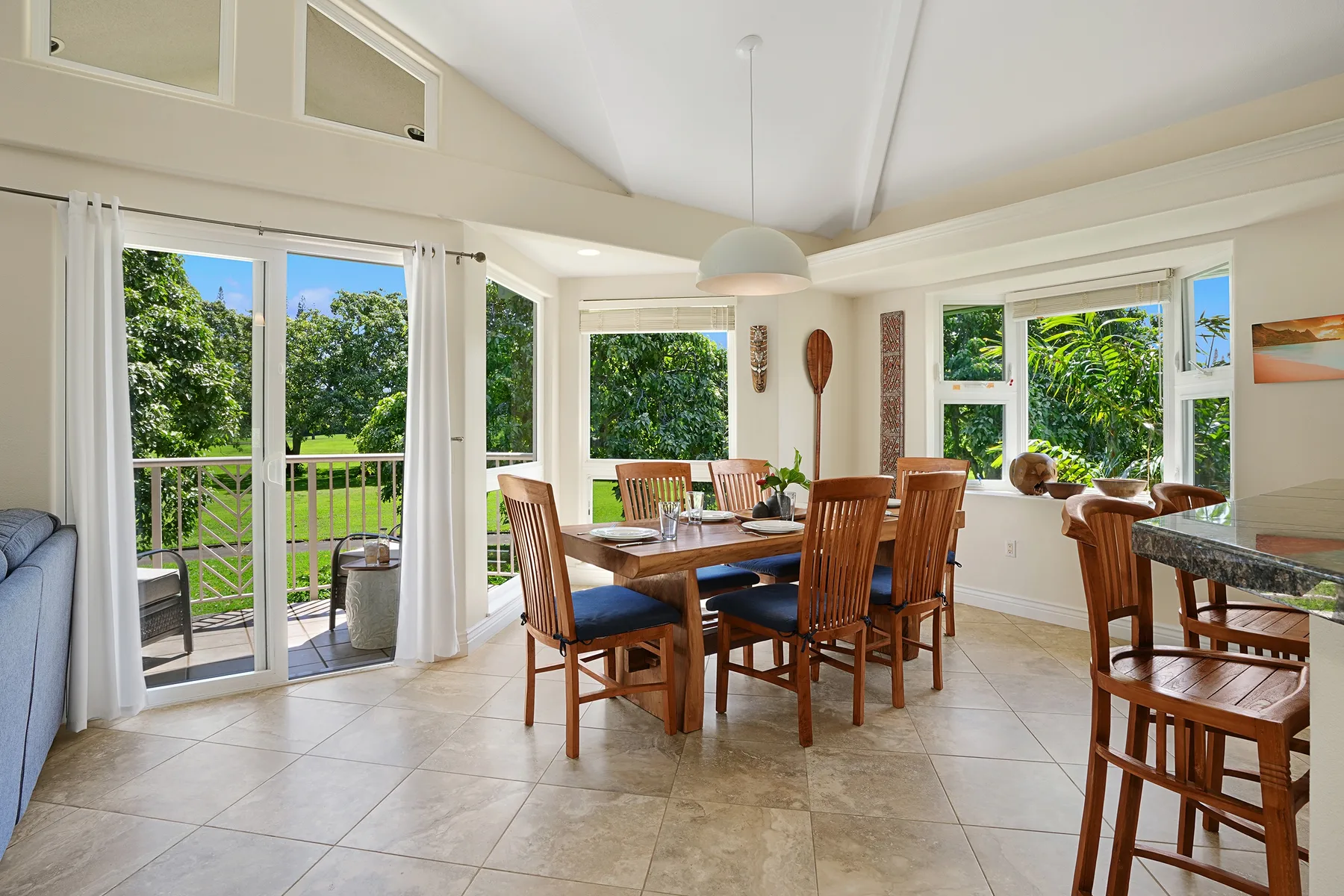 A bright dining area with a wooden table and large windows overlooking greenery.