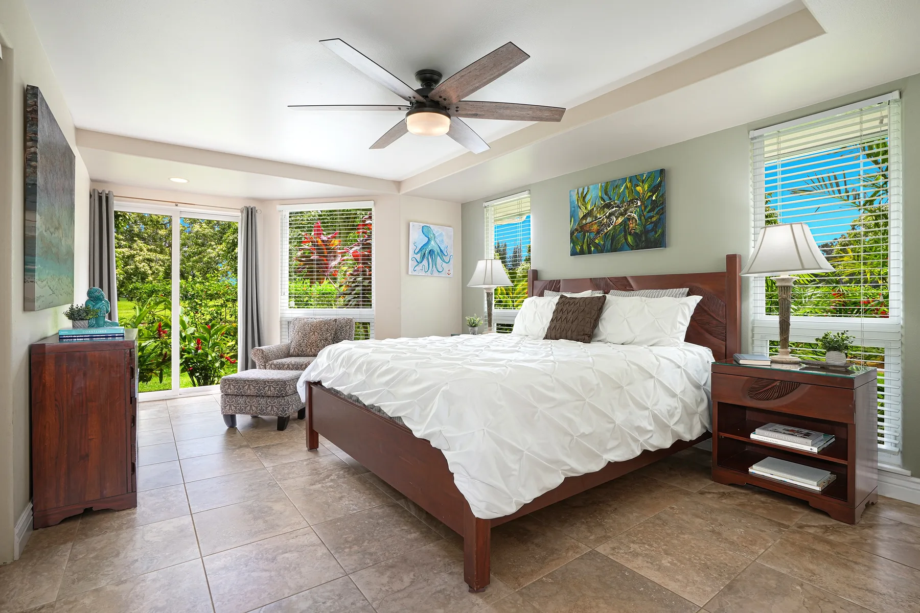 A bright bedroom with a large bed, windows, and colorful artwork.