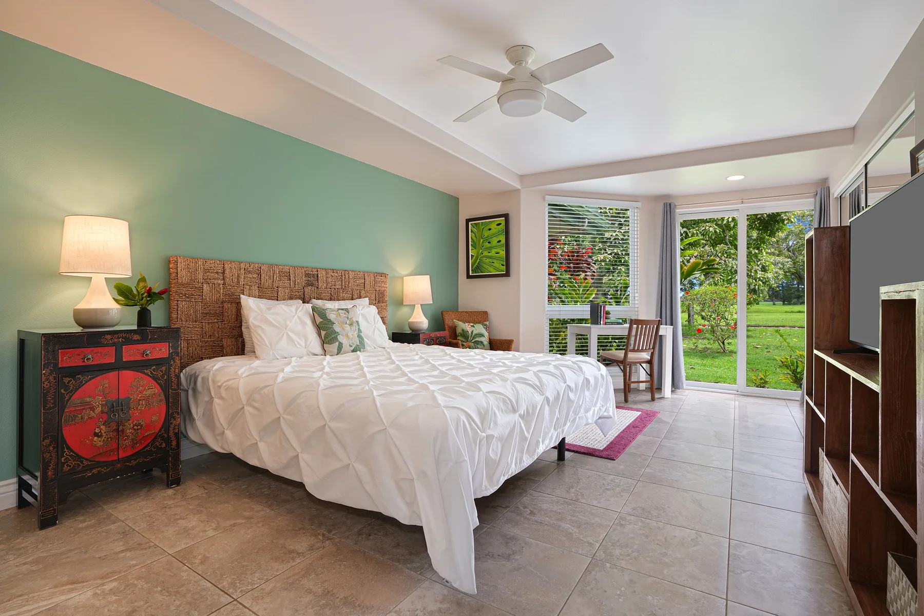 A bright bedroom with a large bed, bedside lamps, and garden-facing windows.