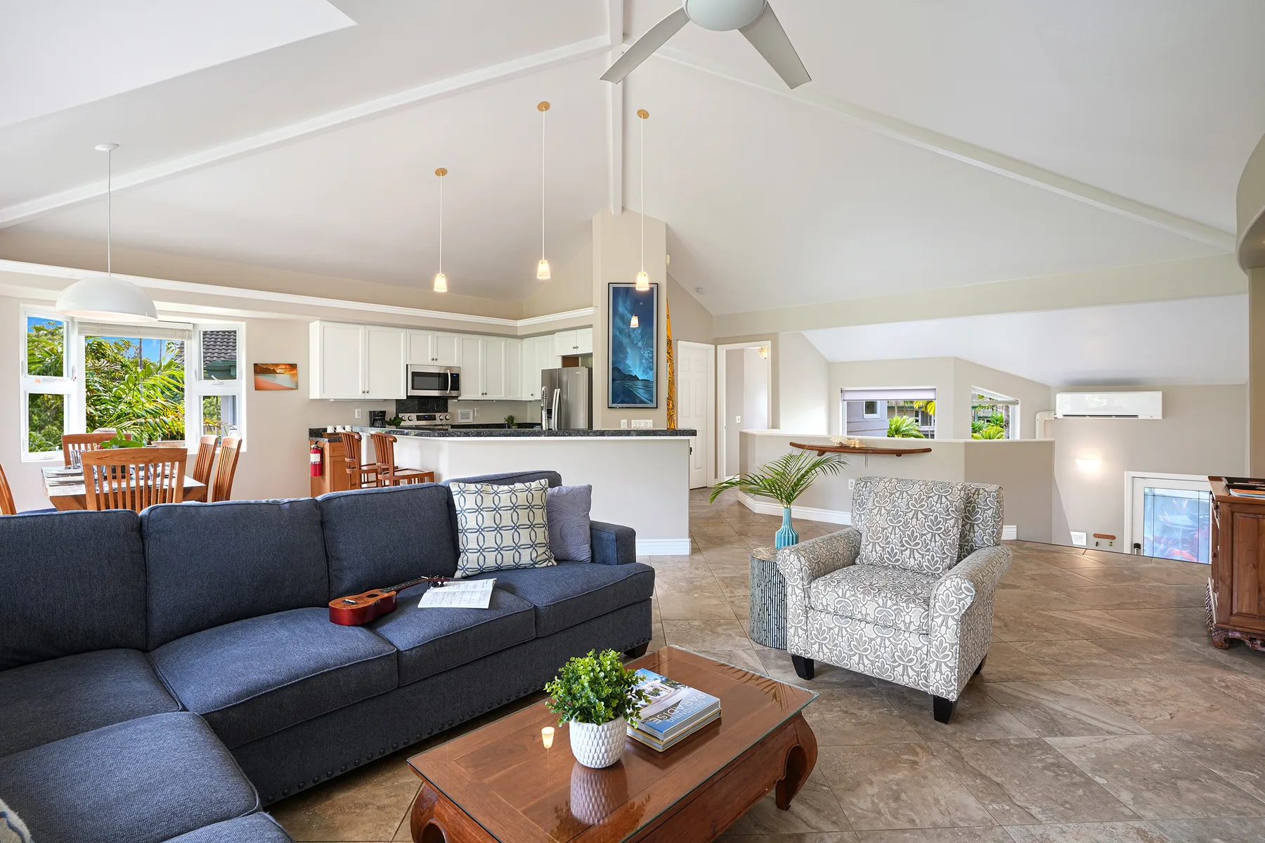 An open-plan living room with a dark sofa and a kitchen beyond.